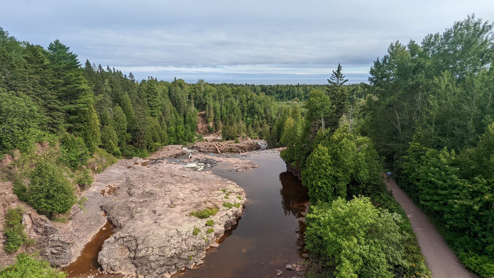 Aerial view of a river winding through a rocky, forested landscape under an overcast sky. - Gooseberry Falls – Upper Falls loop from Gooseberry Falls State Park