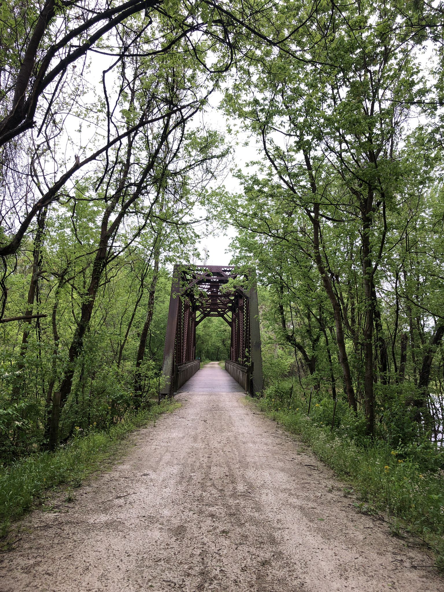 Dirt path leading to a metal truss bridge, surrounded by green trees, overcast. - Defiance – Historic Bridge loop from Matson Hill Park trailhead