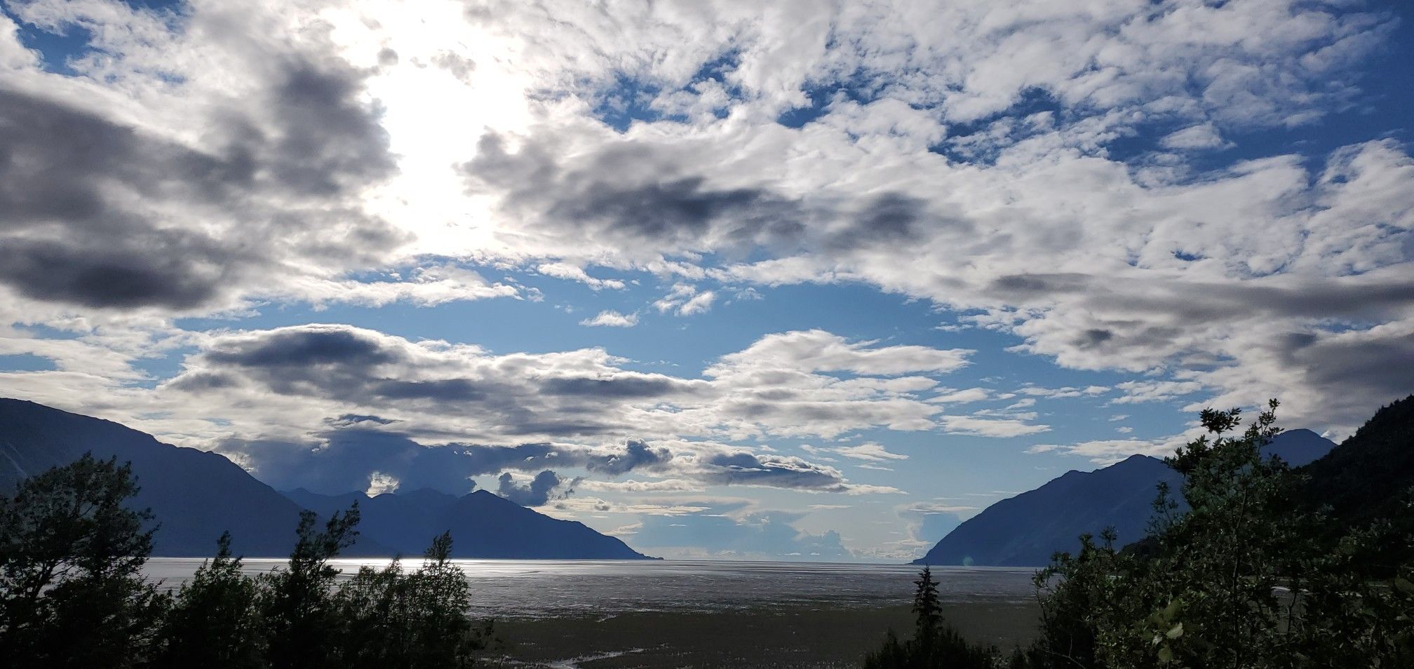 Expansive water body framed by mountains under a dramatic cloudy sky. - Bird to Gird Pathway