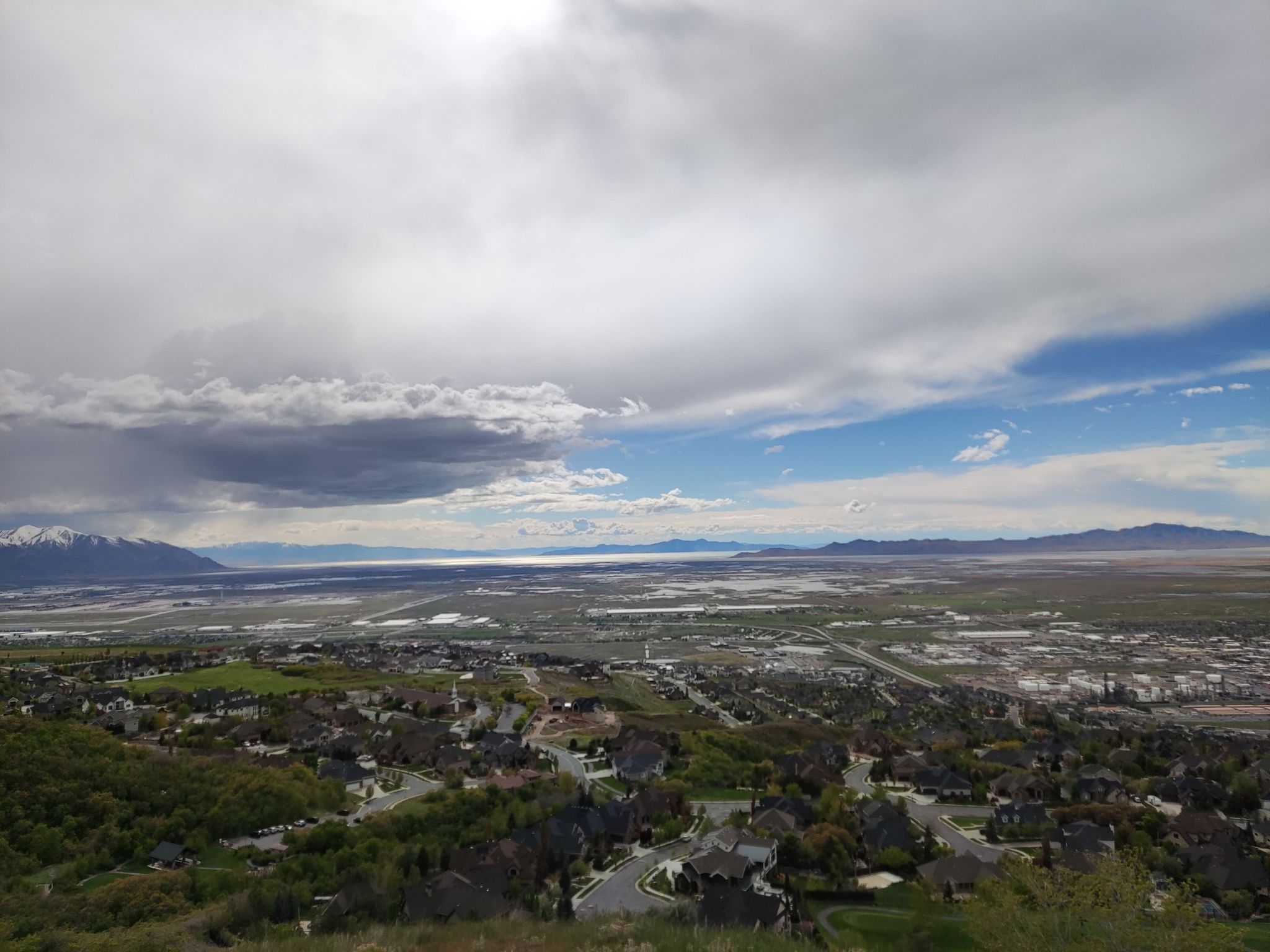 Expansive view of a town, valley, and mountains under a dramatic, partly stormy sky. - Wild Rose Loop