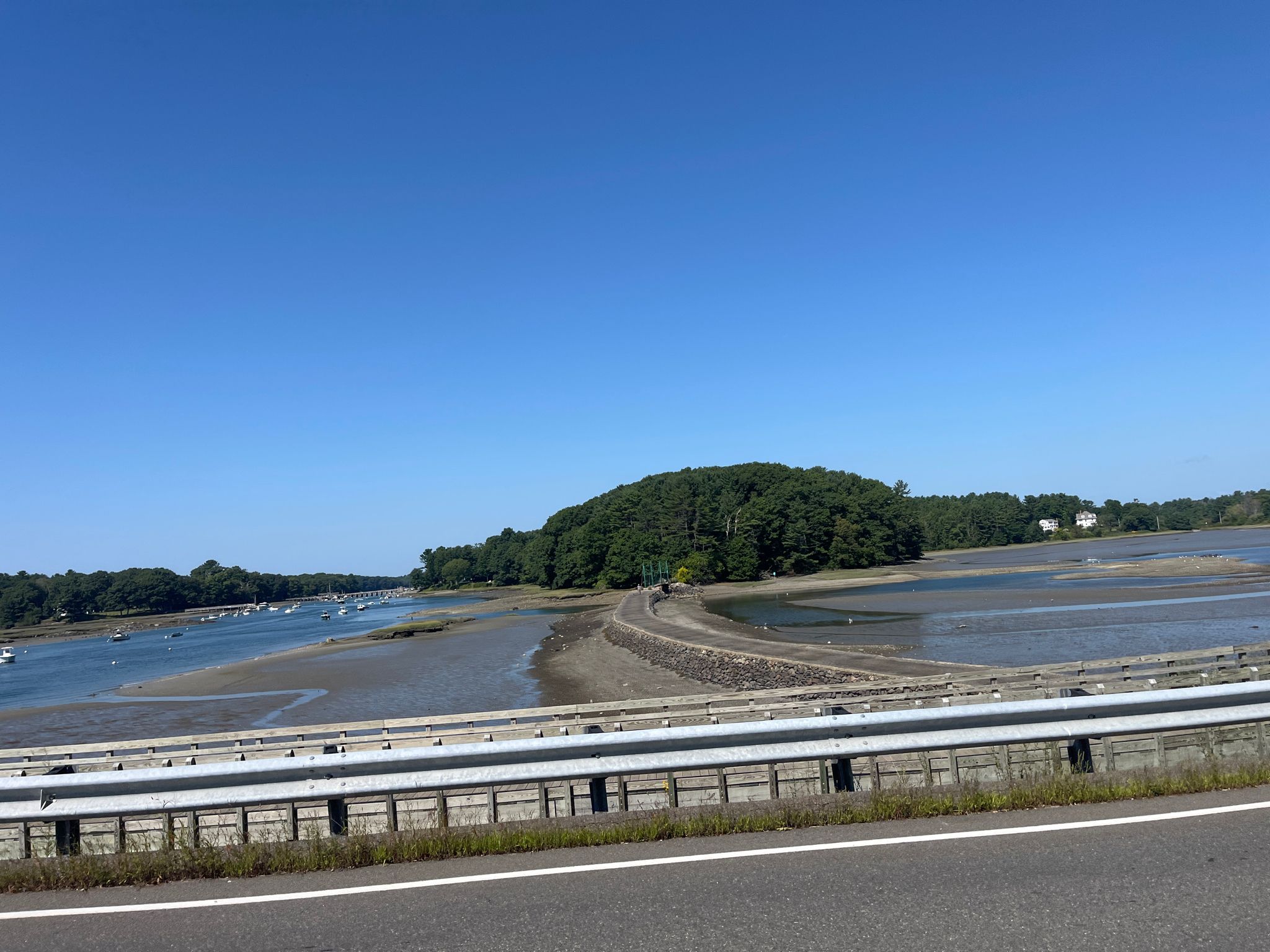 View from a road of a wide coastal inlet with forested land. - Fisherman's Walk to Wiggly Bridge Trail