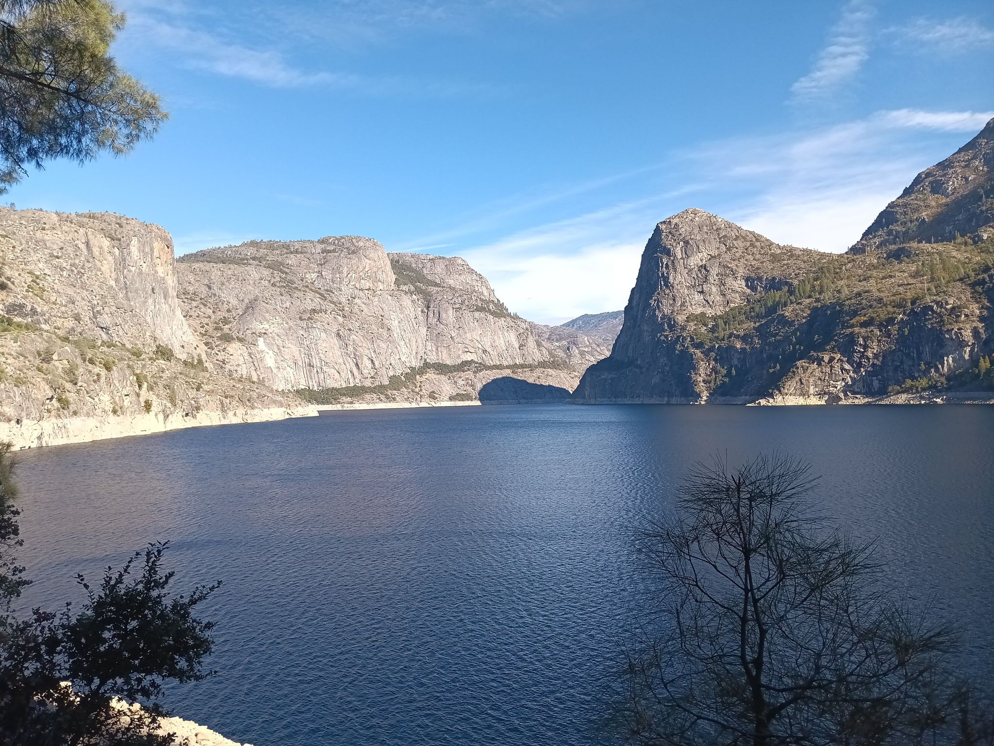 Wide lake surrounded by steep, rocky mountains under a clear blue sky. - Beehive Meadow Trail