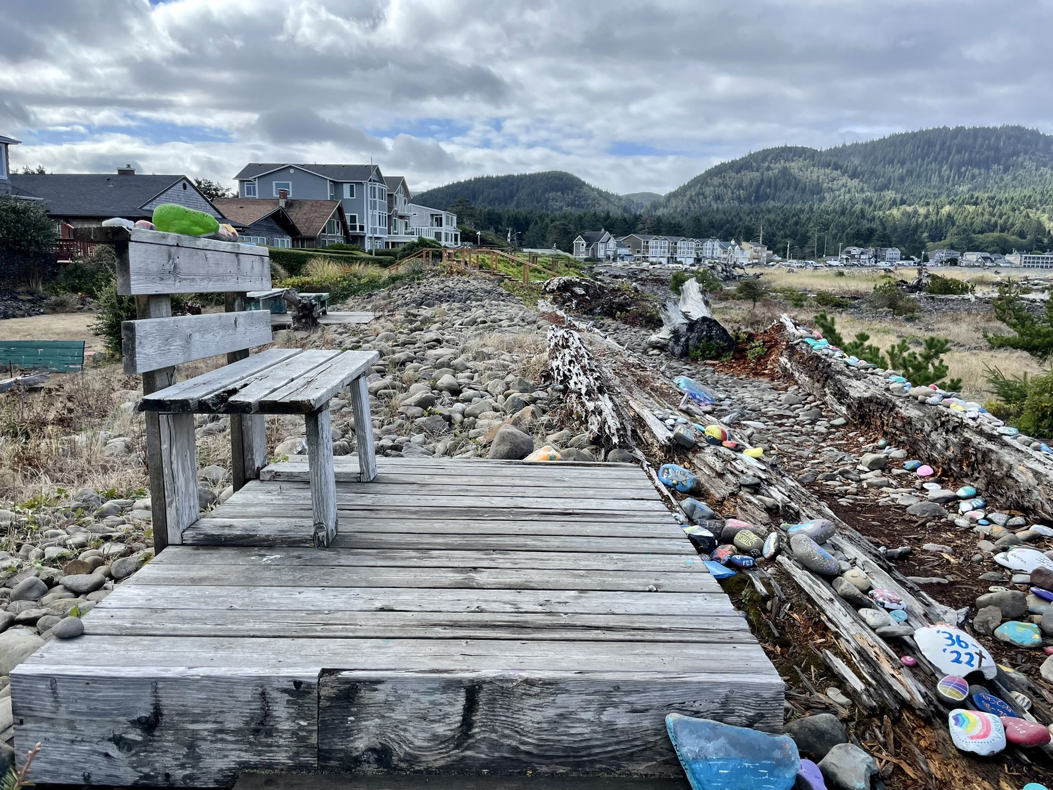 Wooden bench on a platform overlooking a rocky landscape with houses and hills. - Oregon Coast Trail: Seaside Promenade Loop