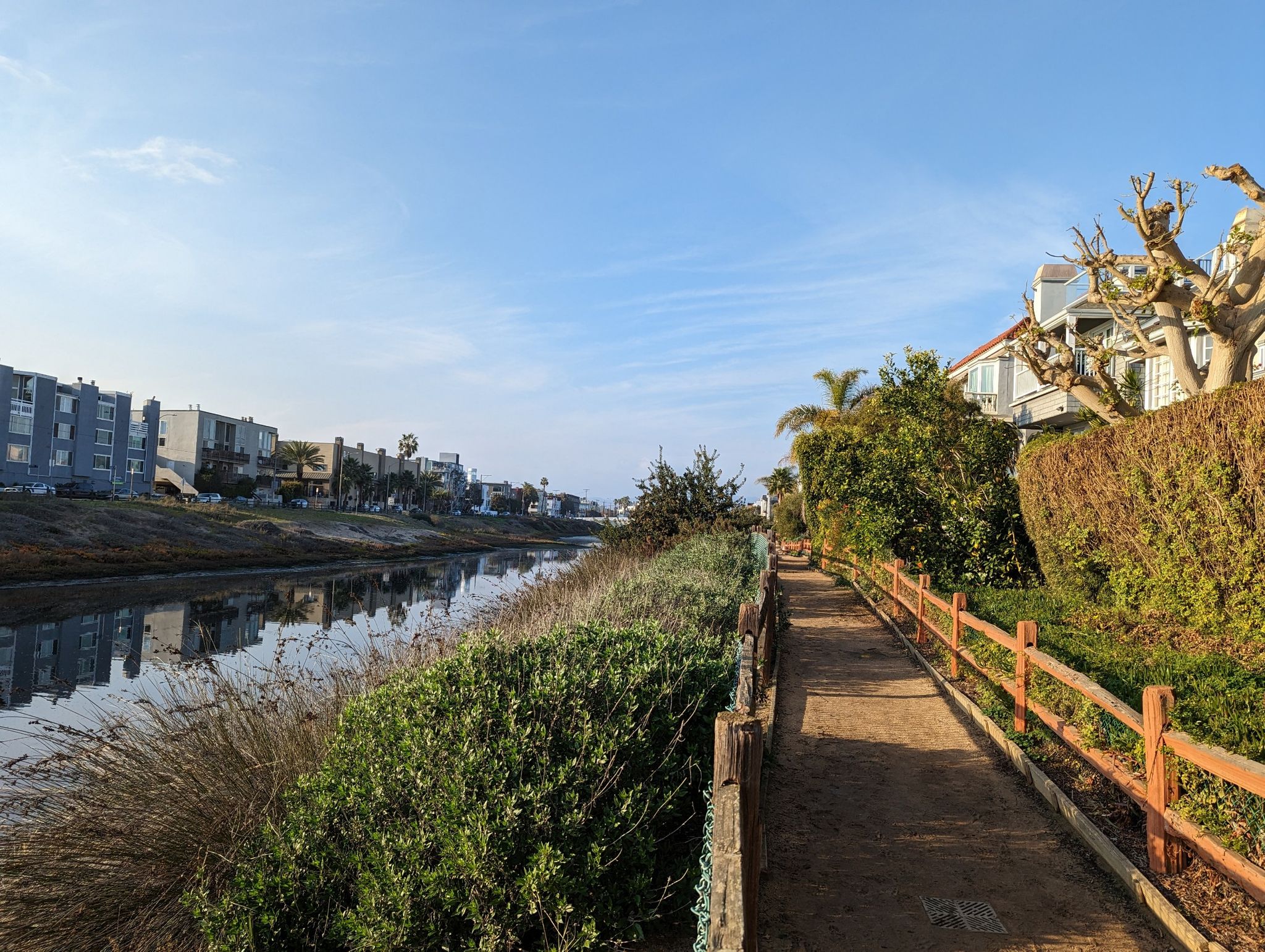 Sunny path beside a canal with buildings and lush greenery. - Santa Monica Pier – Venice Beach Boardwalk loop from Santa Monica State Beach