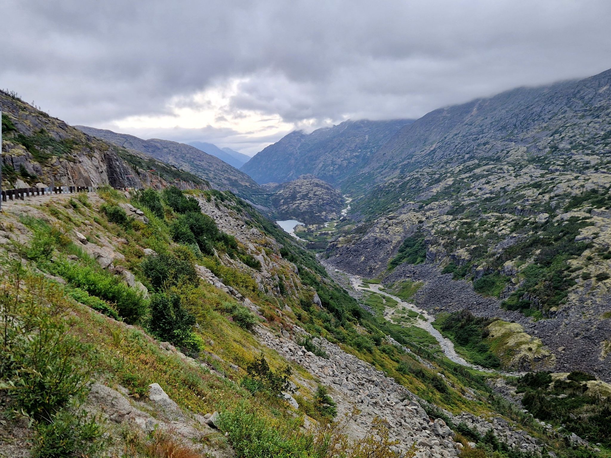 Panoramic view of a deep mountain valley with a river and distant lake. - Skagway to White Pass