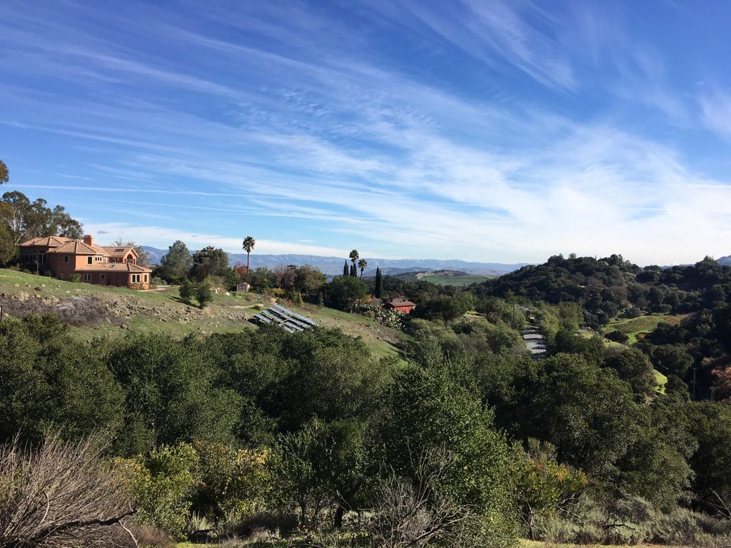 A sunny hillside with a large house, green trees, and distant mountains. - Kennedy Trail – Kennedy Road loop from Oak Meadow