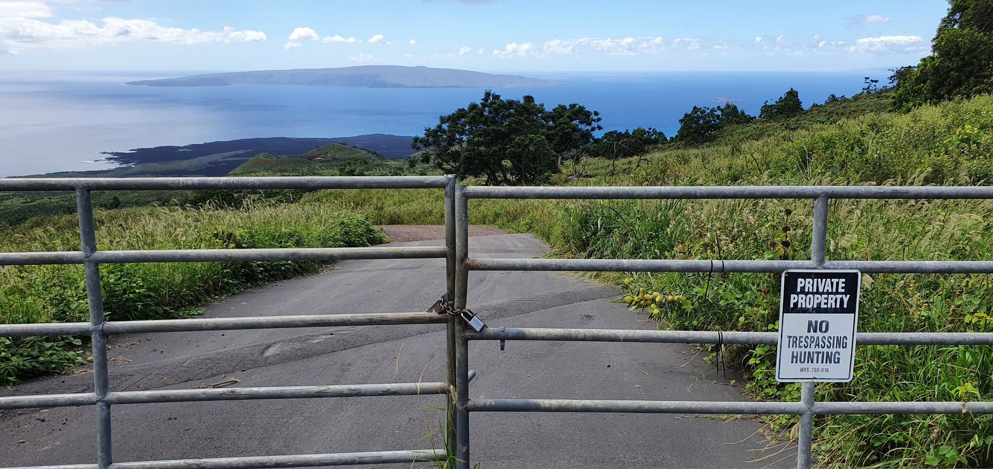 Closed metal gate on a paved road, with a "Private Property" sign and ocean view. - Pukalani to the Windmills loop —Kula Forest Reserve