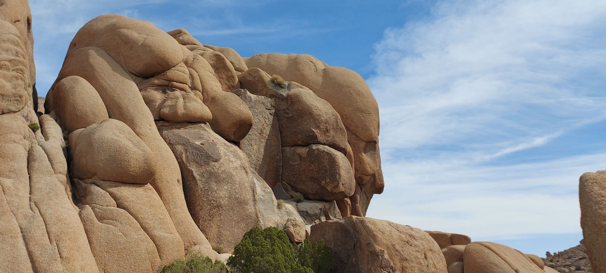 Massive stacked rock formations under a partly cloudy blue sky. - Split Rock and Skull Rock Loop Trail