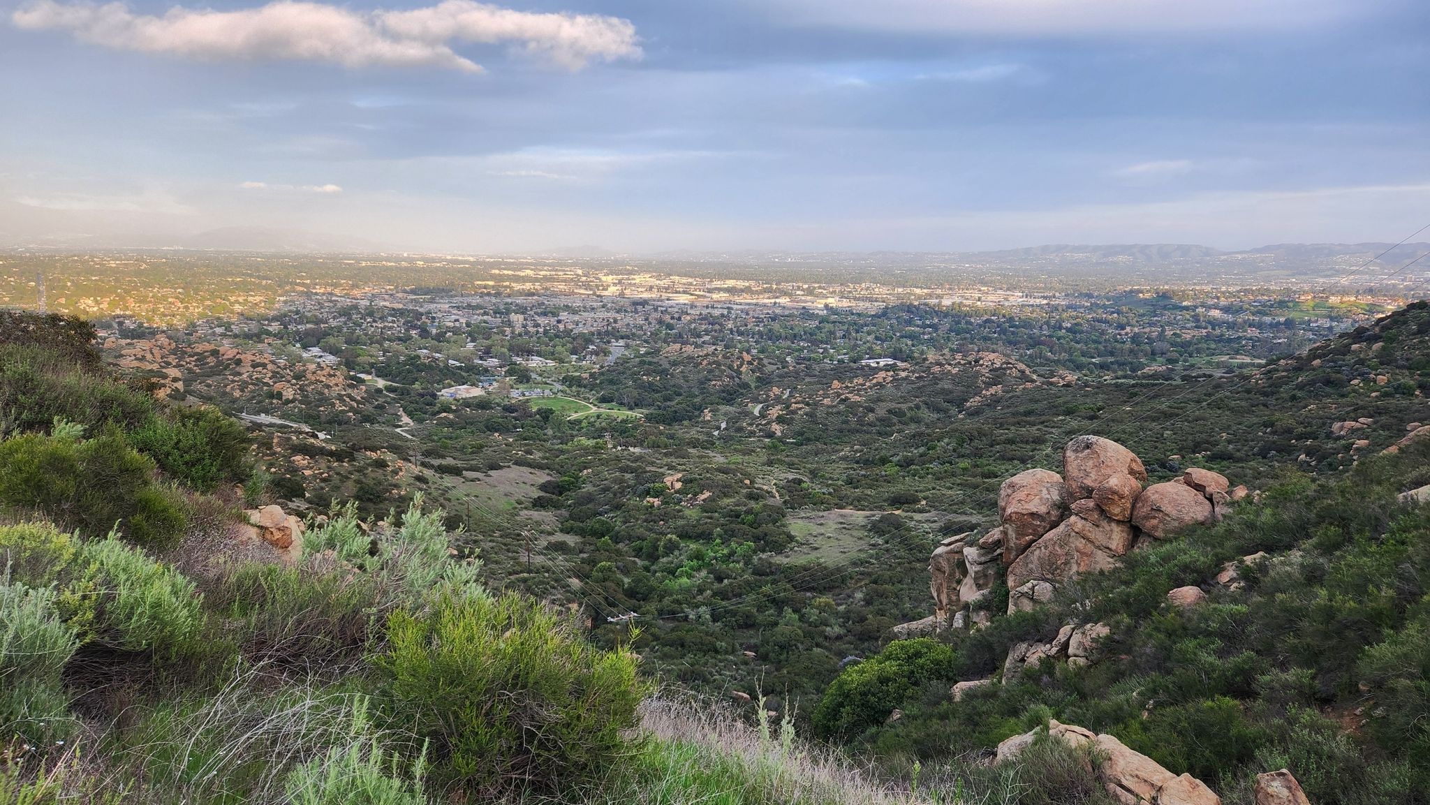 Expansive valley view with rocky hills, green brush, and a distant city. - Spahn Ranch via Mattingly, Sanchez, and El Camino Nuevo Trail