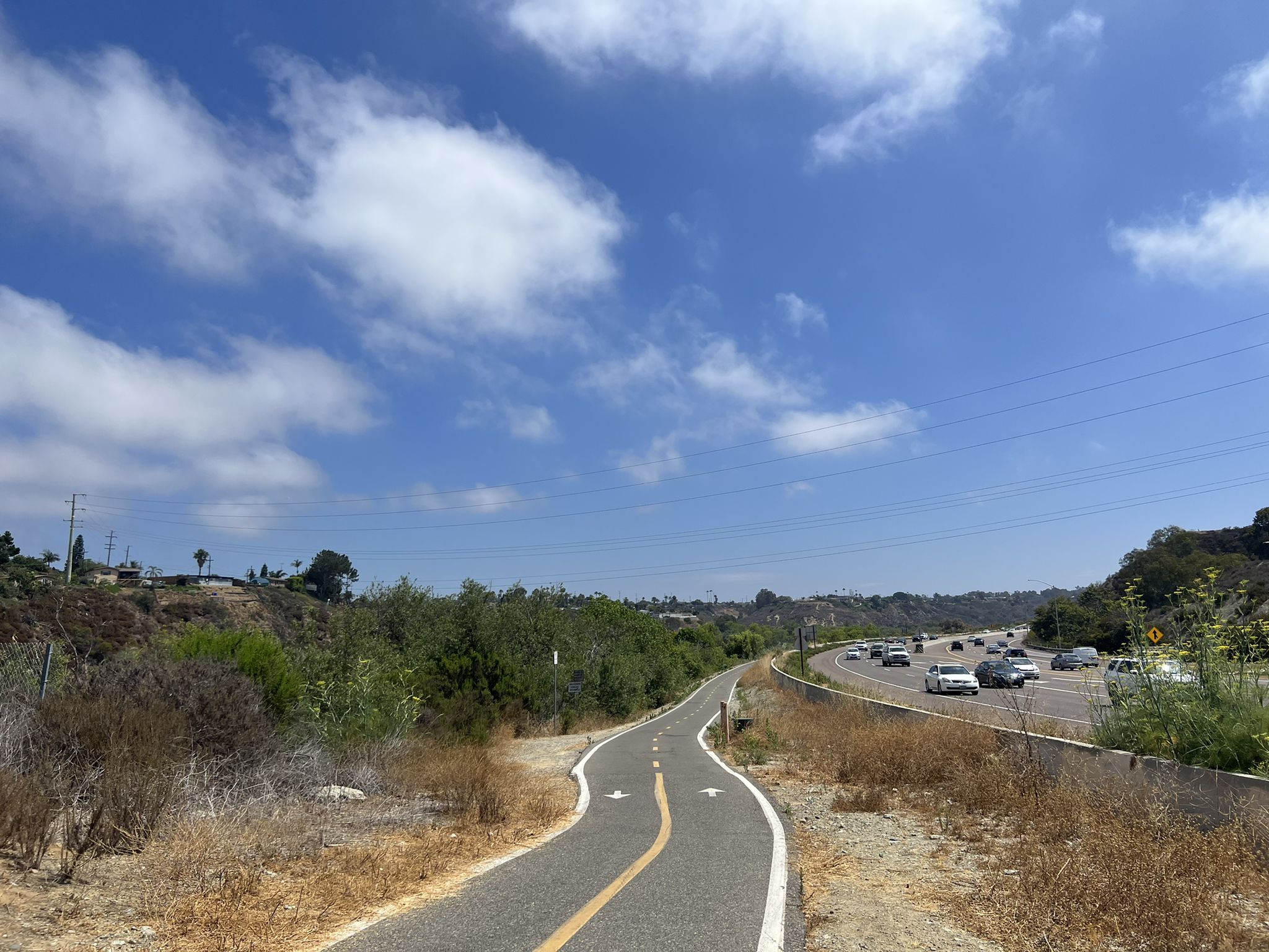 Paved path alongside a busy highway under a bright, cloudy sky. - San Luis Rey River Trail