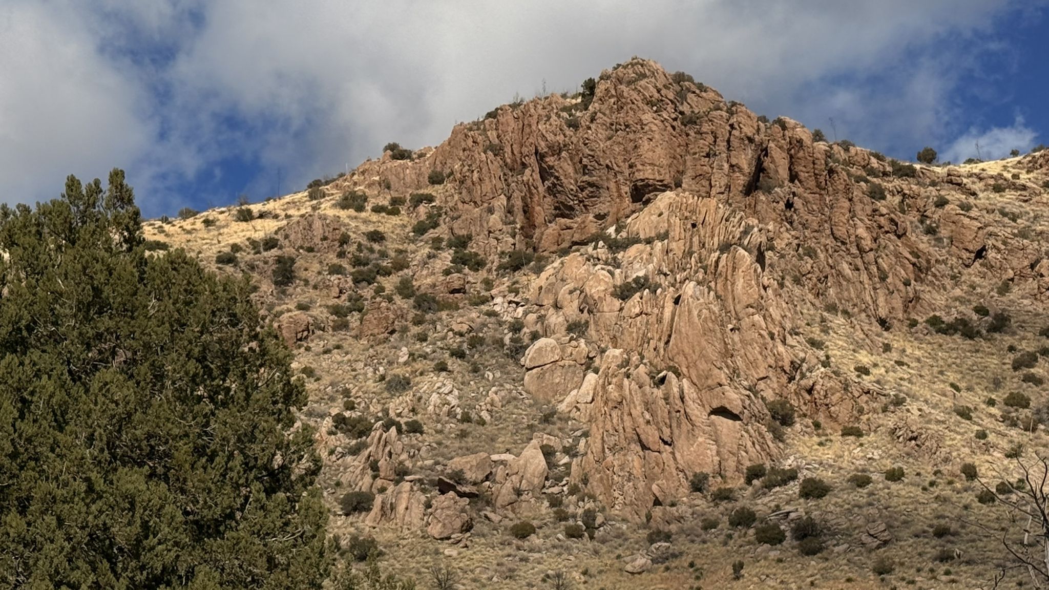 Close-up of a rugged, rocky mountain face under a blue sky. - Silver Spur Meadow Trail