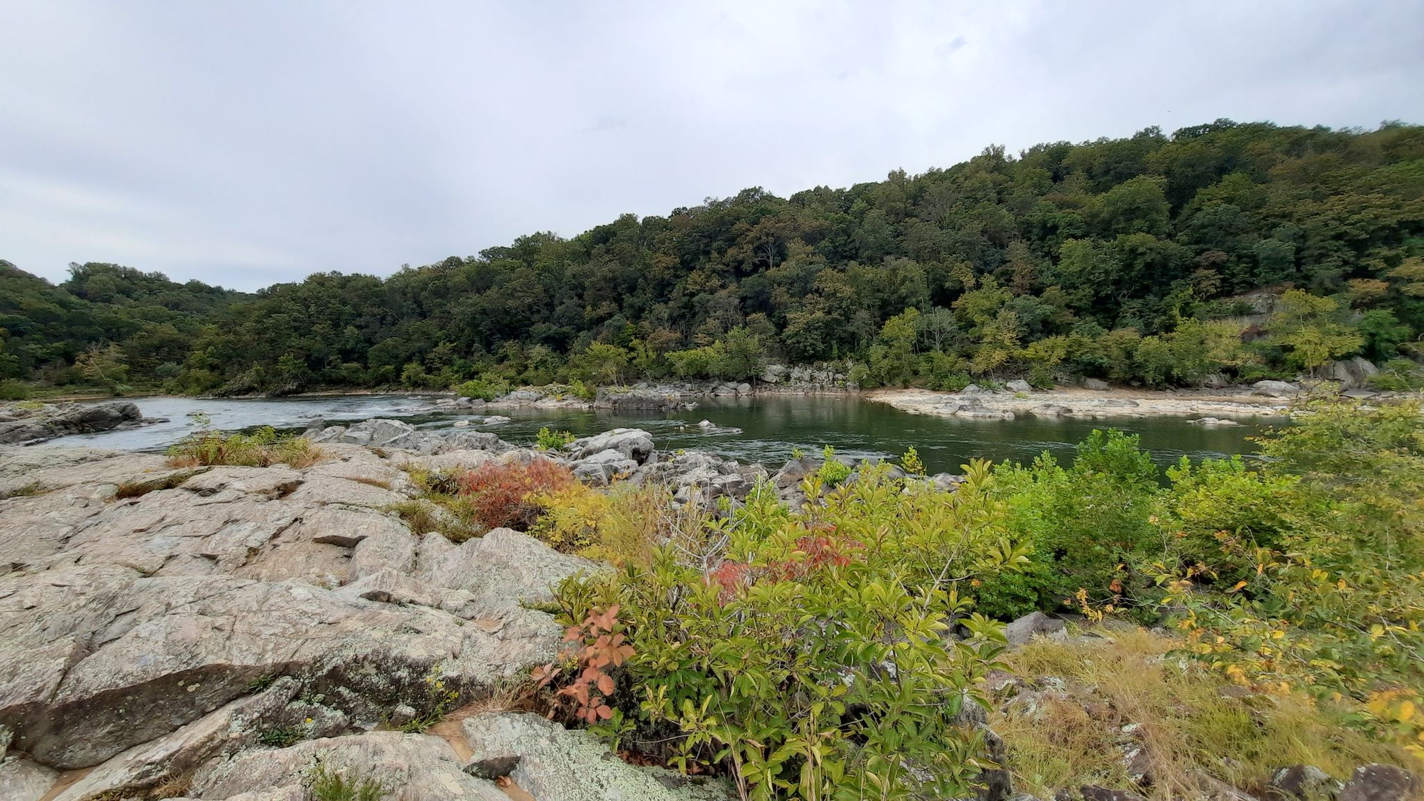 Rocky river landscape with colorful bushes and green trees under a cloudy sky. - Berma Road and Woodland Trail Loop