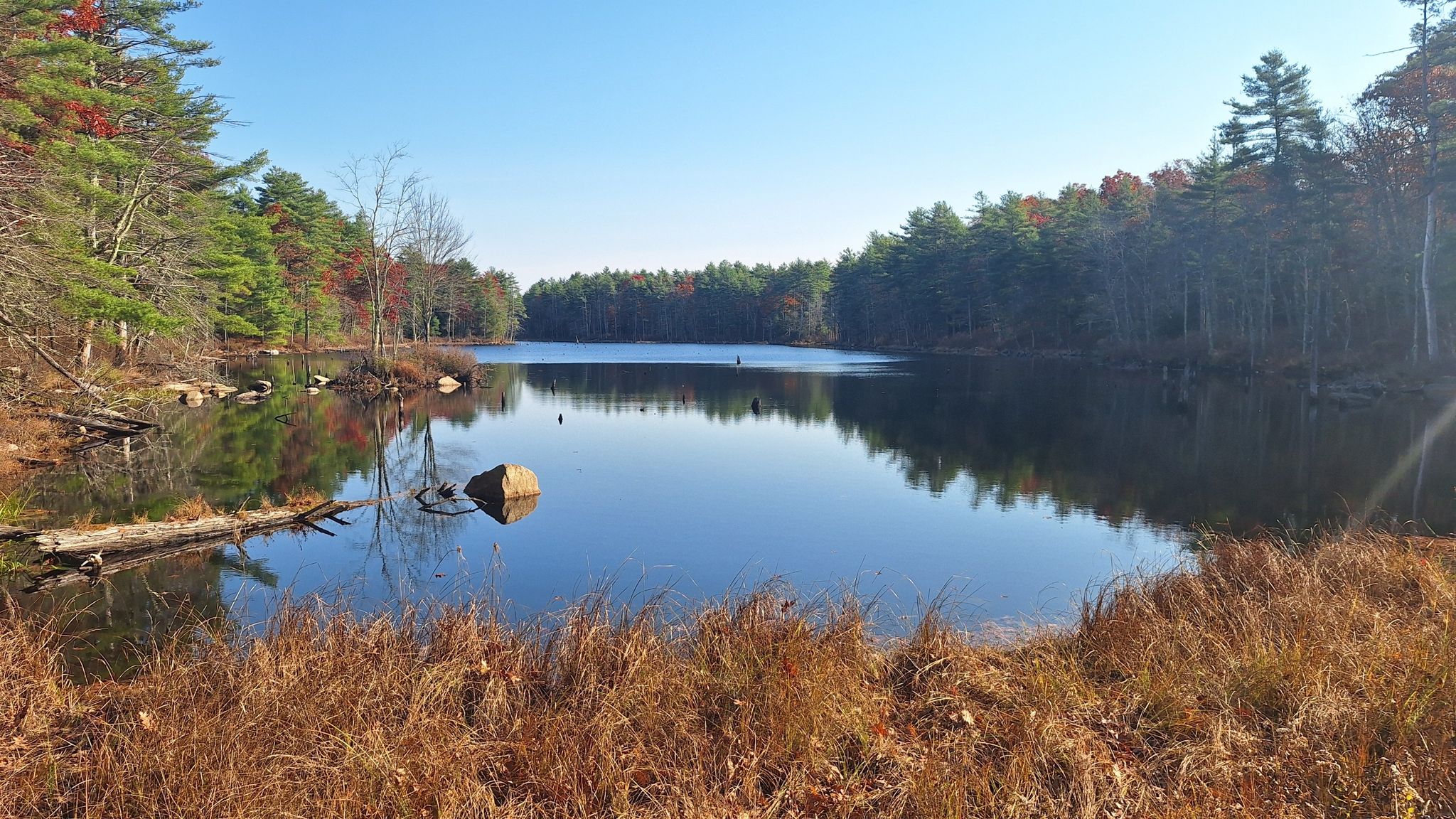 Wide view of a tranquil lake reflecting autumn trees under a clear sky. - North South Trail: Chepachet to Burrillville