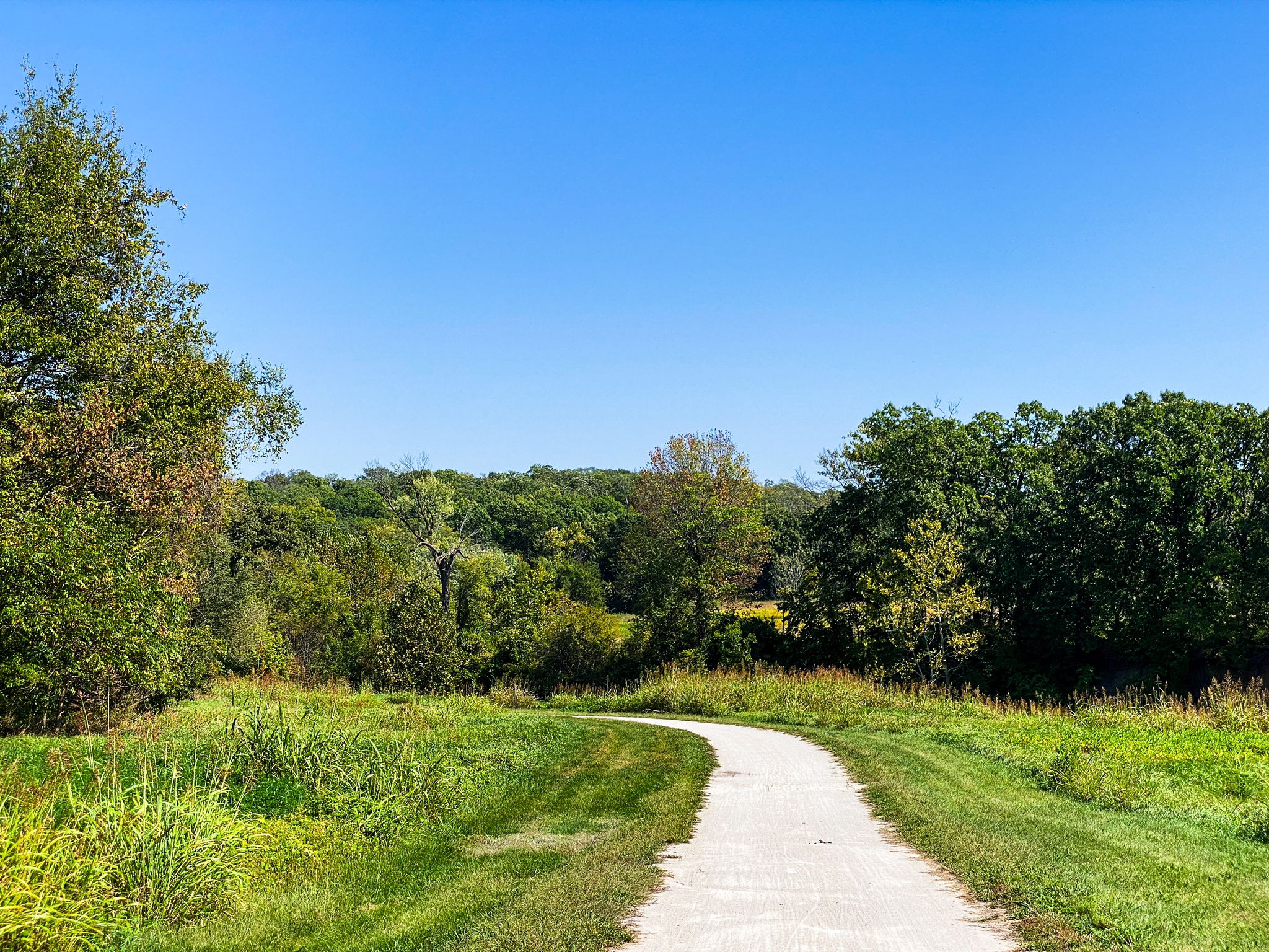 A winding gravel path through green fields and distant trees under blue sky. - Little Blue Trace Trail loop from Little Blue River