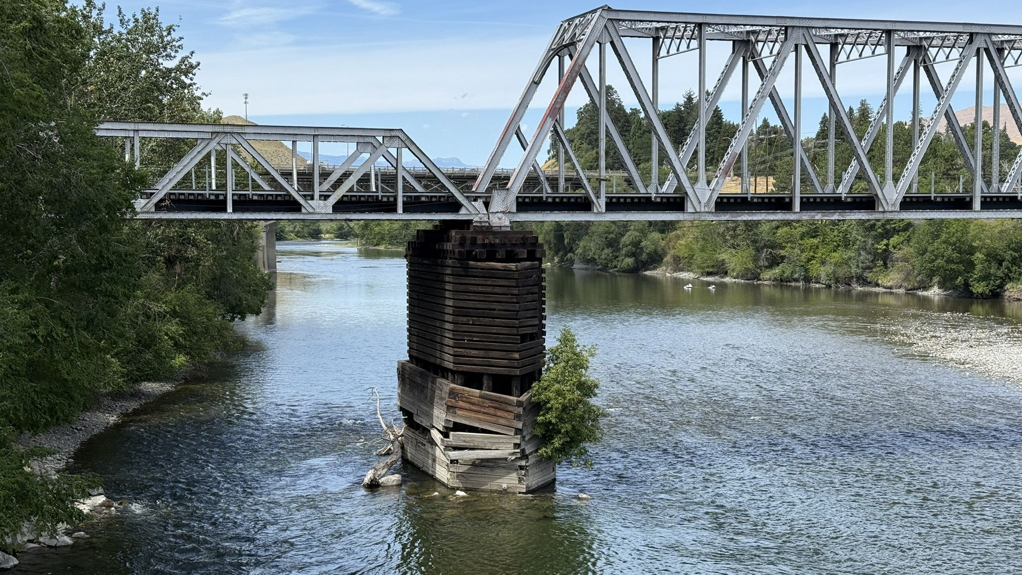 Metal truss bridge over a river, green trees on banks, bright day. - Wenatchee Confluence Trail
