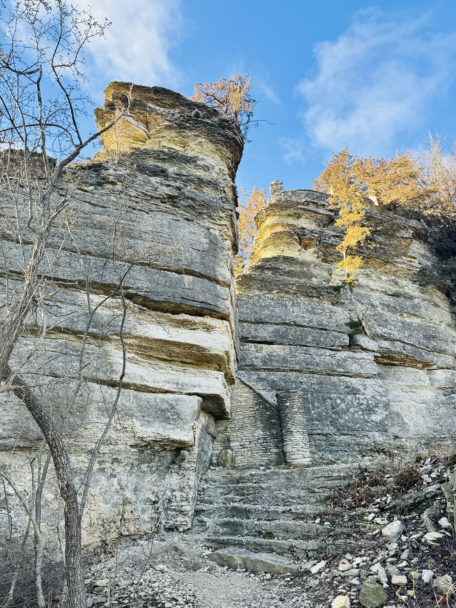 Tall, layered rock formations with stone steps under a bright blue sky. - Pulpit Rock loop from Decorah