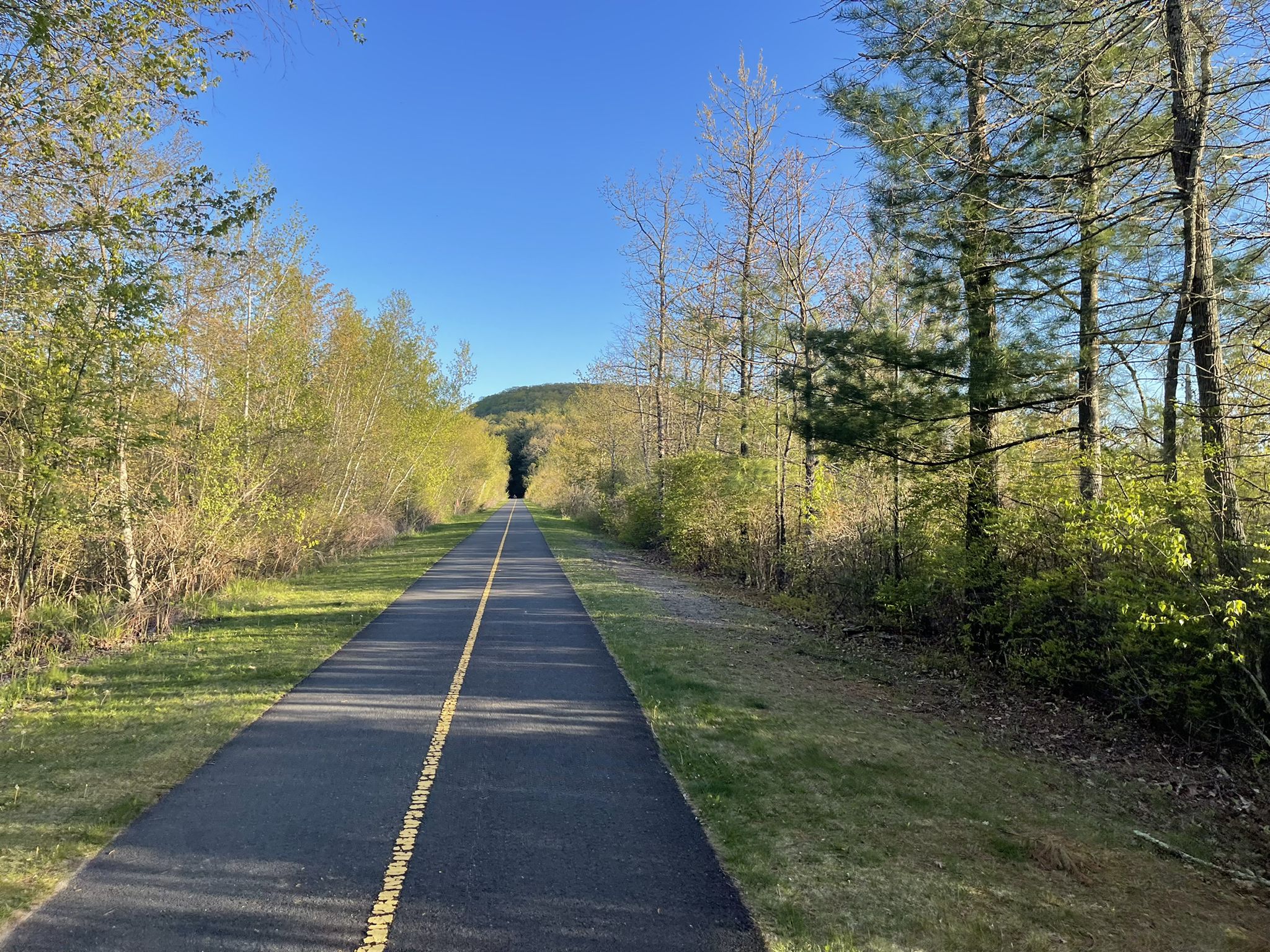 Long paved path with yellow line, leading towards a distant hill. - Southwick Rail Trail loop from Halmar, Inc. (Partridge Meadow)