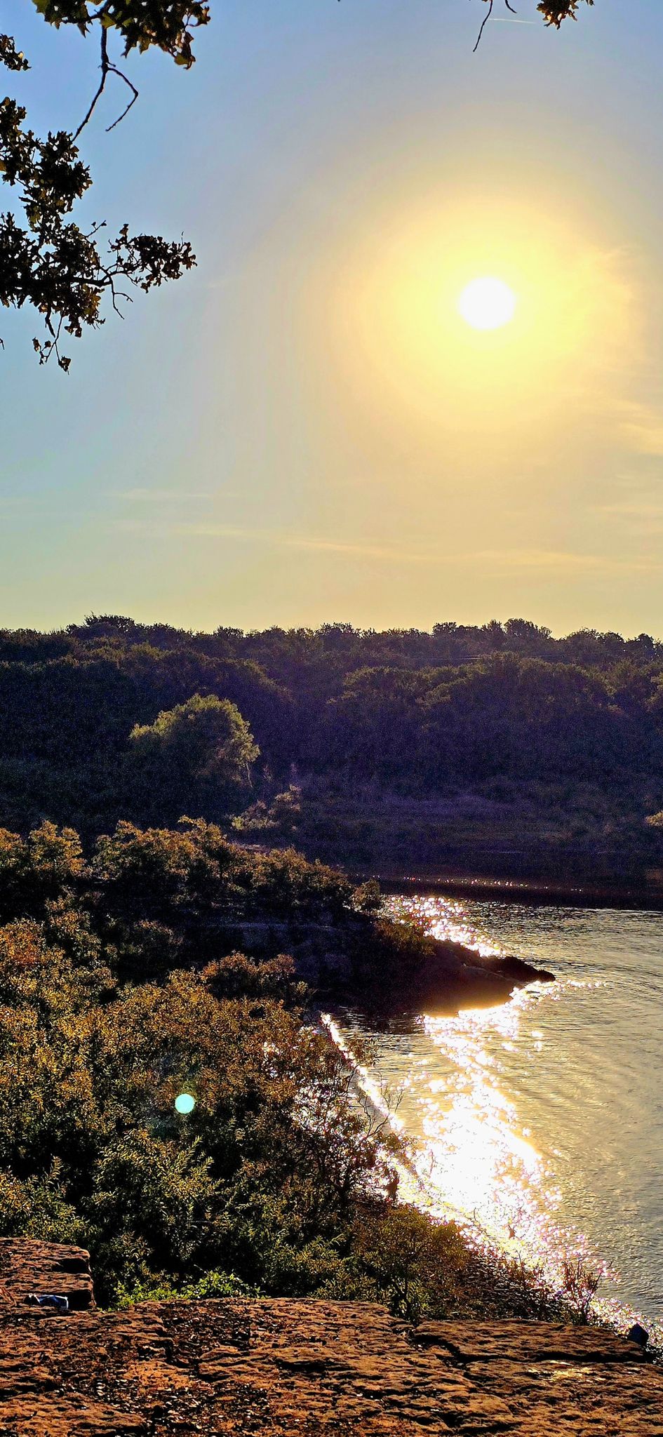 Bright sun over a lake with sparkling water, framed by trees. - Lakeside View at Murrell Park loop from Bluebonnet Park