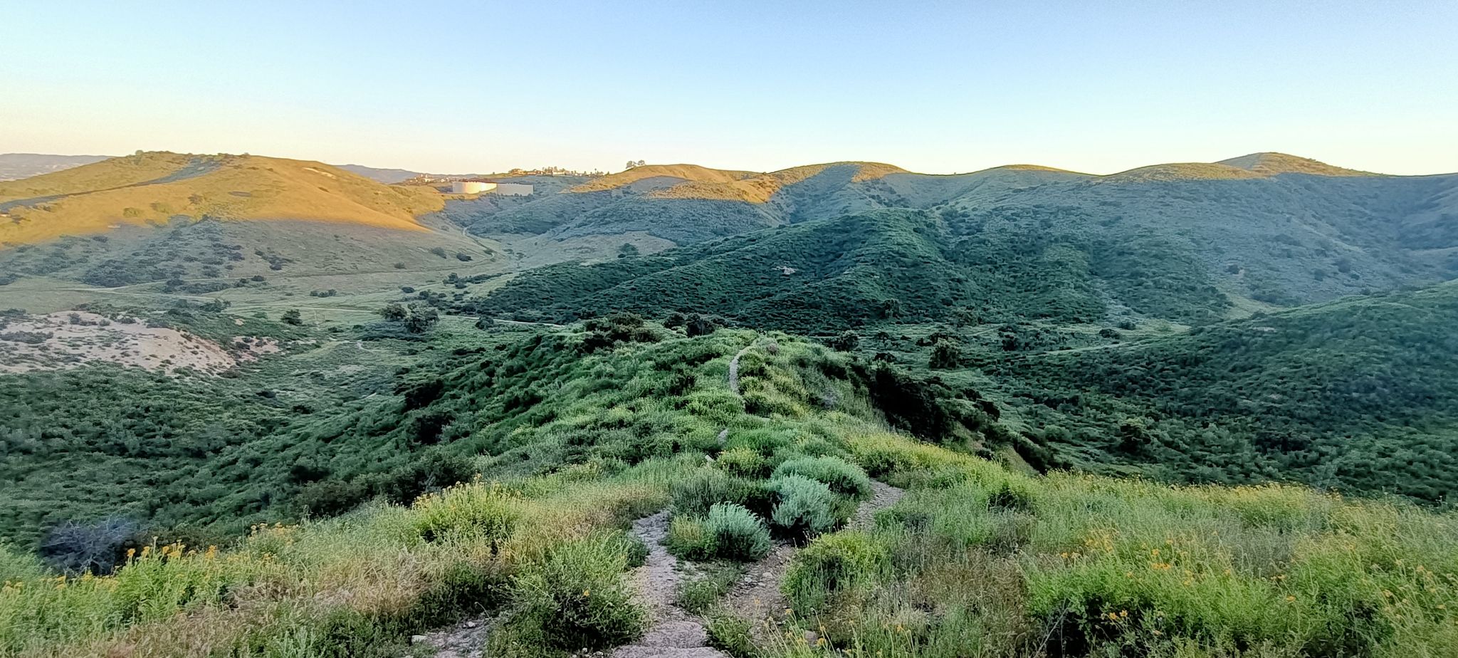 Panoramic view of green rolling hills and valleys under a clear sky. - Cave of Munits to Castle Peak Canyoneering Route