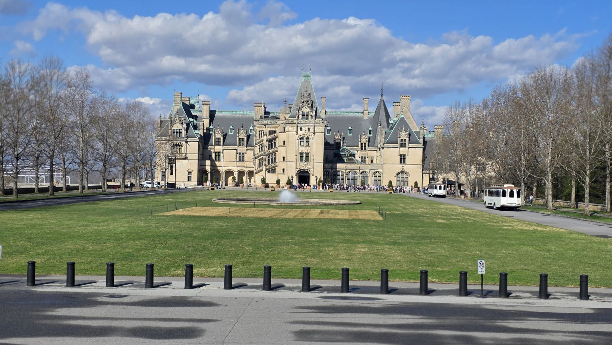 Grand historic building with a fountain on a green lawn under a partly cloudy sky. - Gardens loop