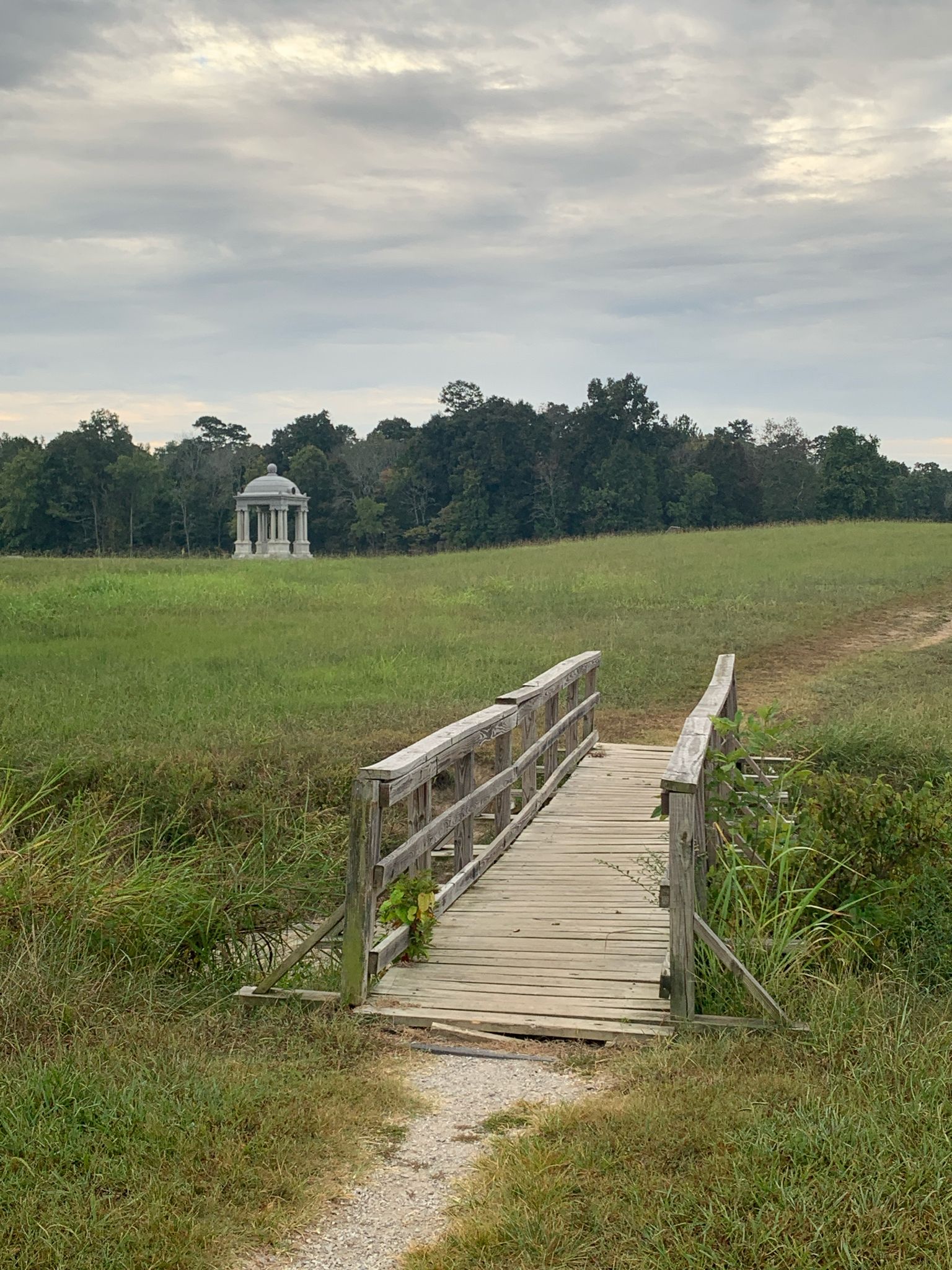 Wooden footbridge over grass leading to a distant white gazebo under cloudy skies. - Chickamauga & Chattanooga National Military Park loop
