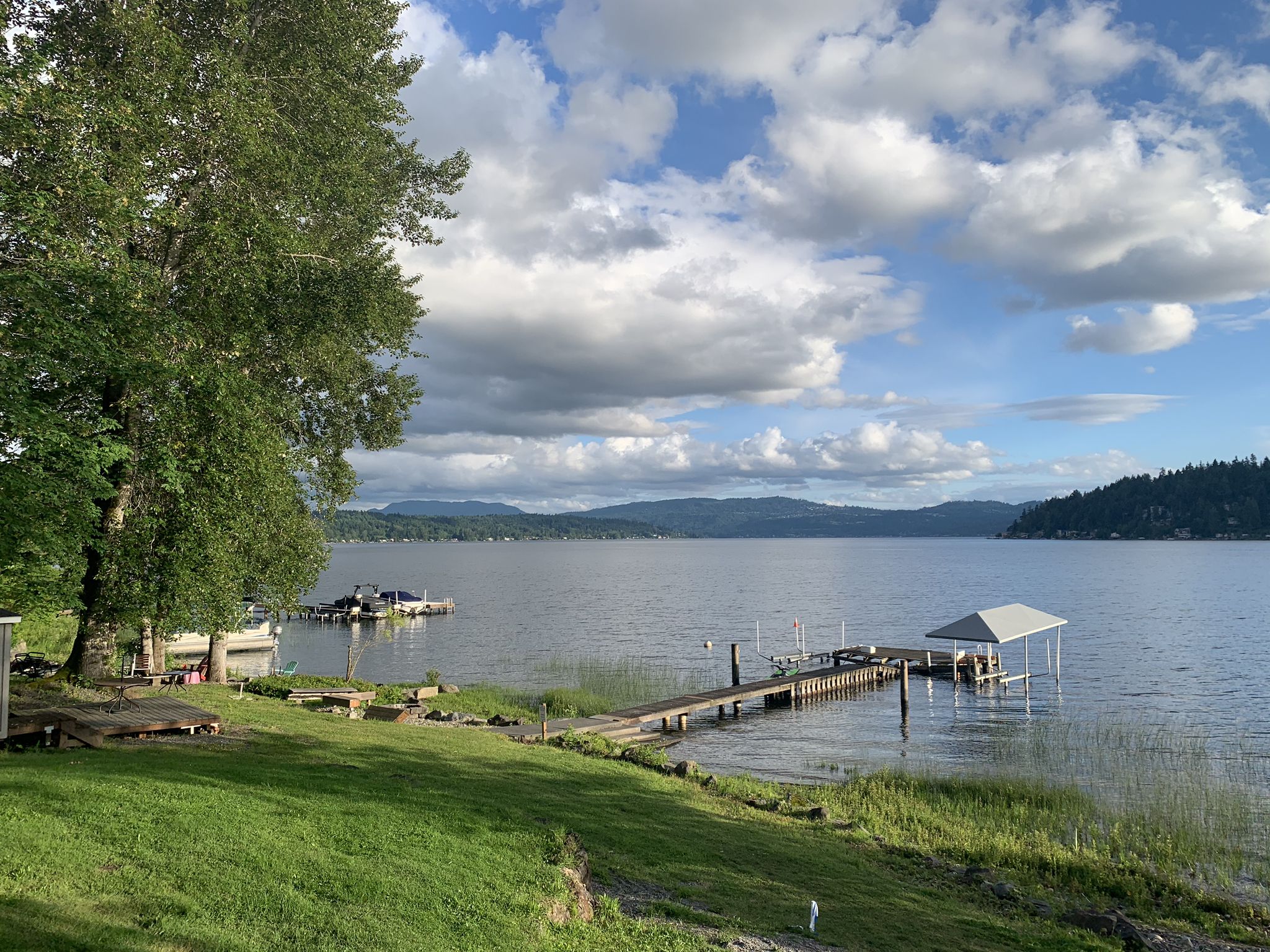 Bright, sunny day over a lake with a dock, covered slip, and distant mountains. - Lake Sammamish Loop Trail