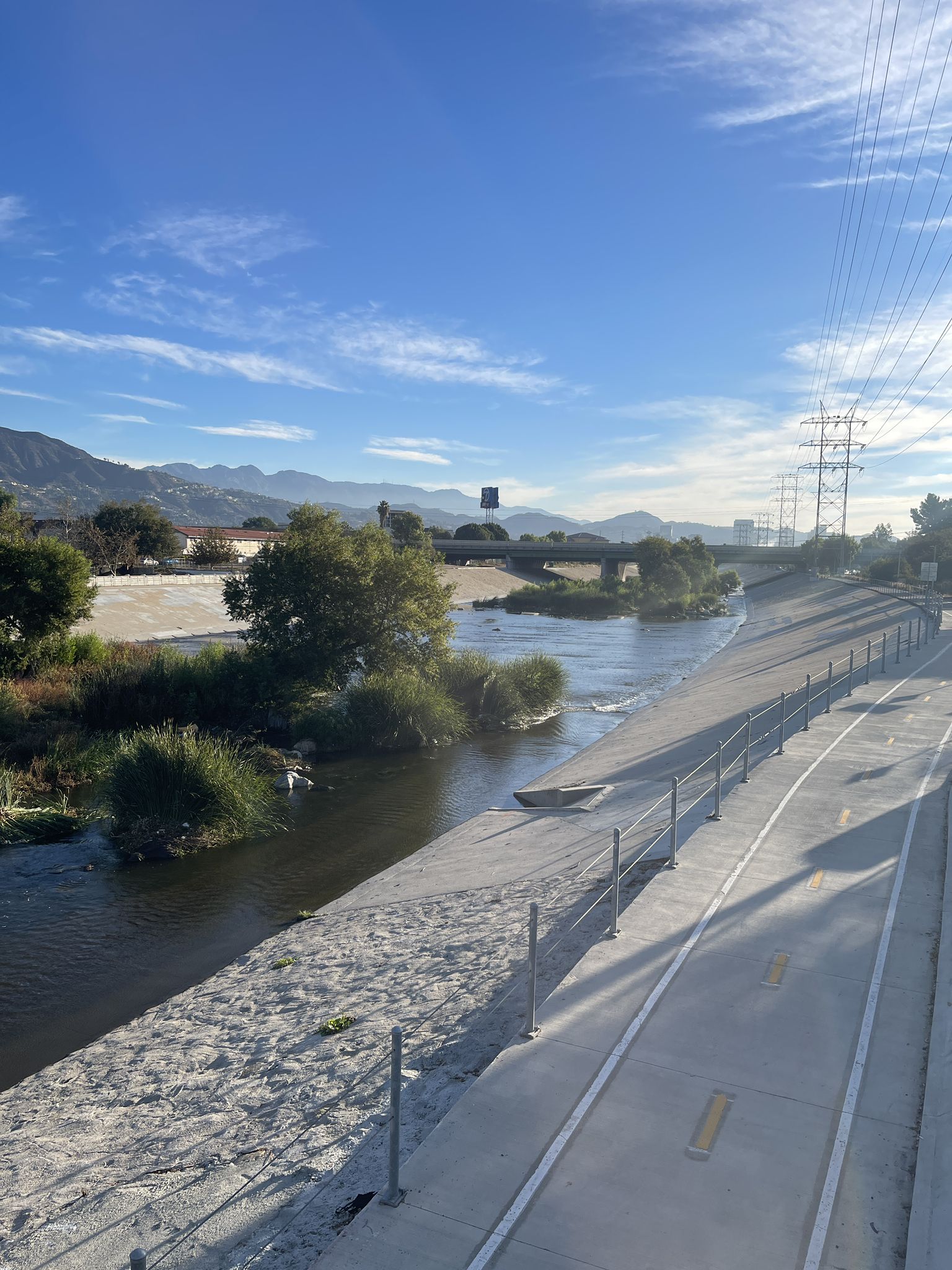 Paved path next to a river in a concrete channel, mountains, sunny. - Railway yard with steam trains – Toyon Trail loop from DreamWorks Studios