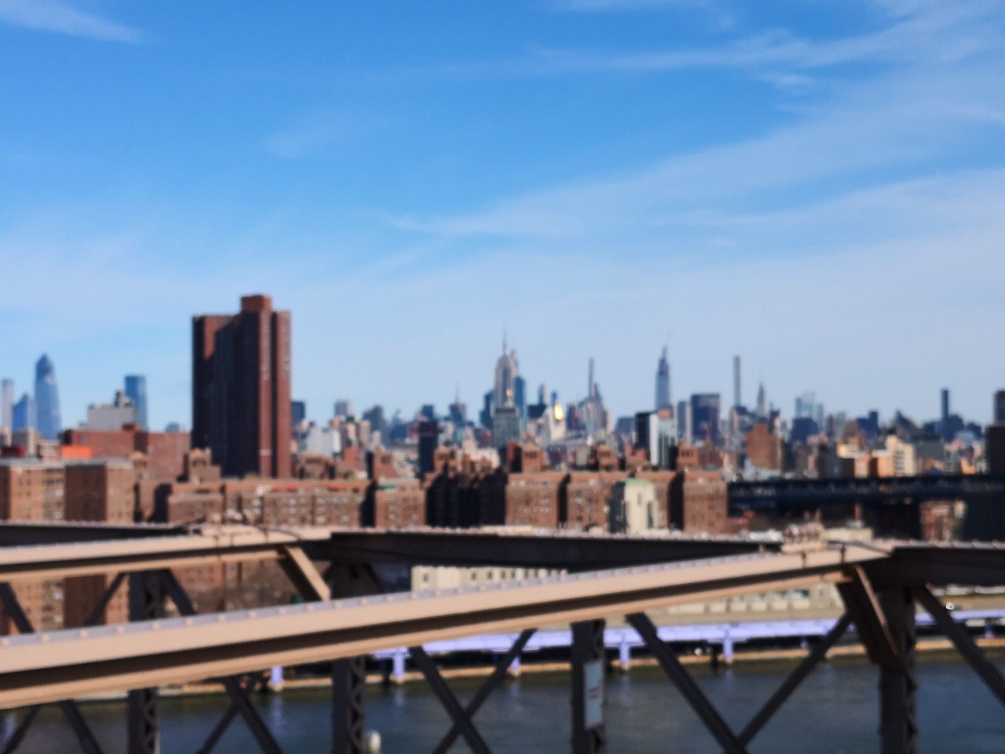 City skyline with tall buildings, seen from a bridge on a clear day. - Brooklyn Bridge Walk