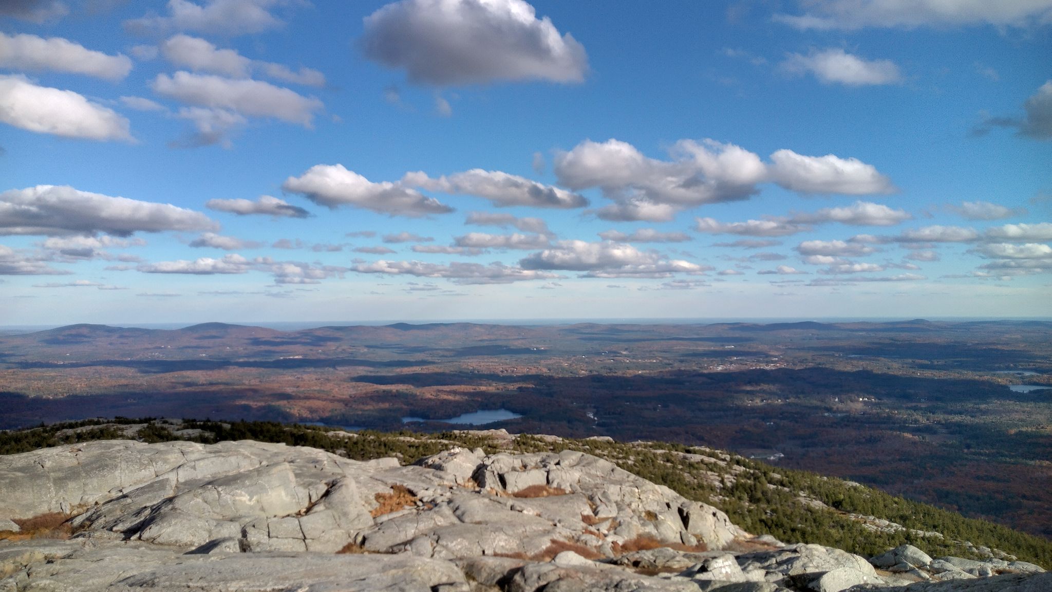 Rocky mountain top overlooking a vast autumn landscape under a blue sky. - Dublin Trail