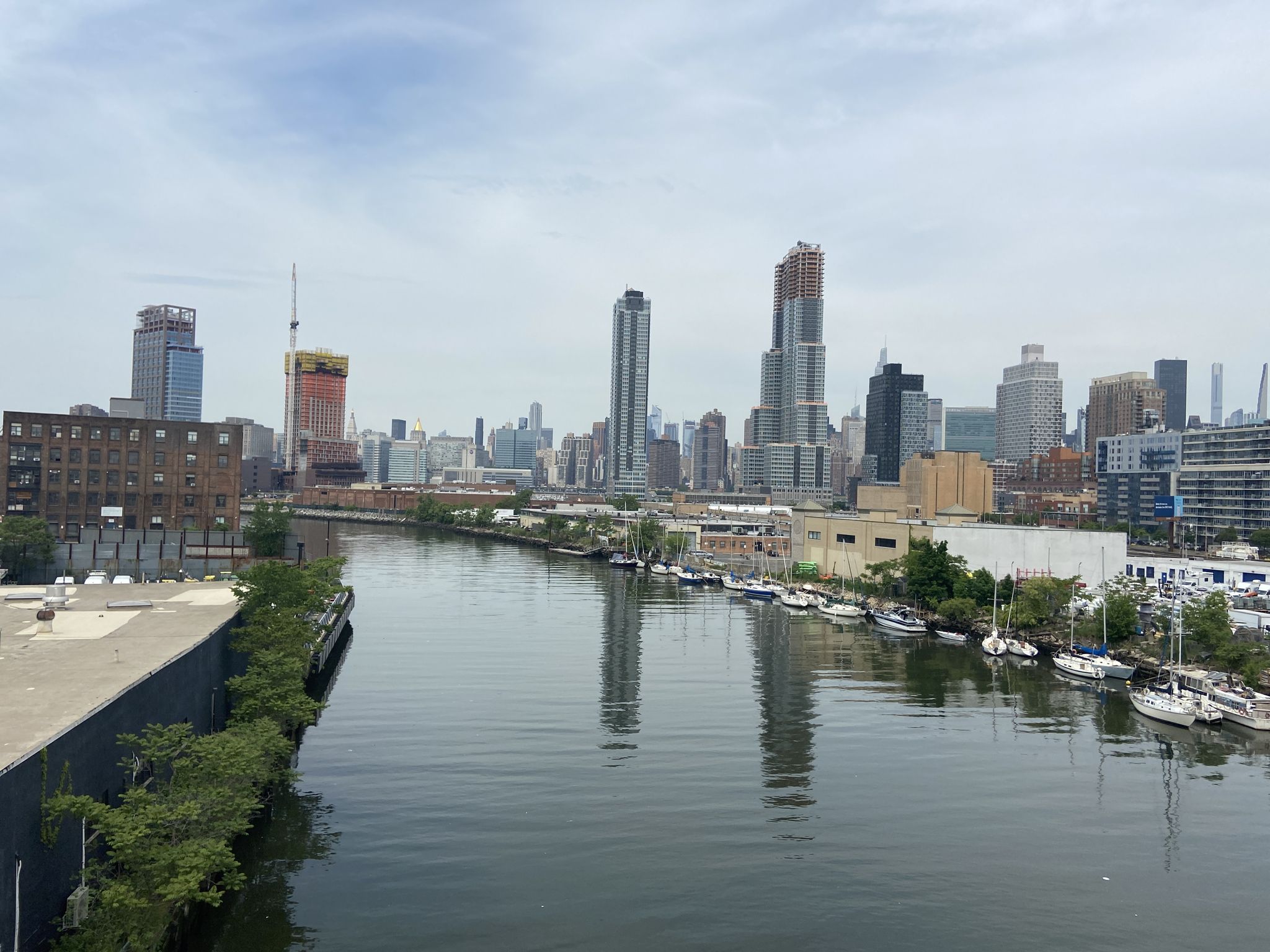 River reflecting a dense city skyline with boats docked along the banks. - Brooklyn loop via Prospect Park