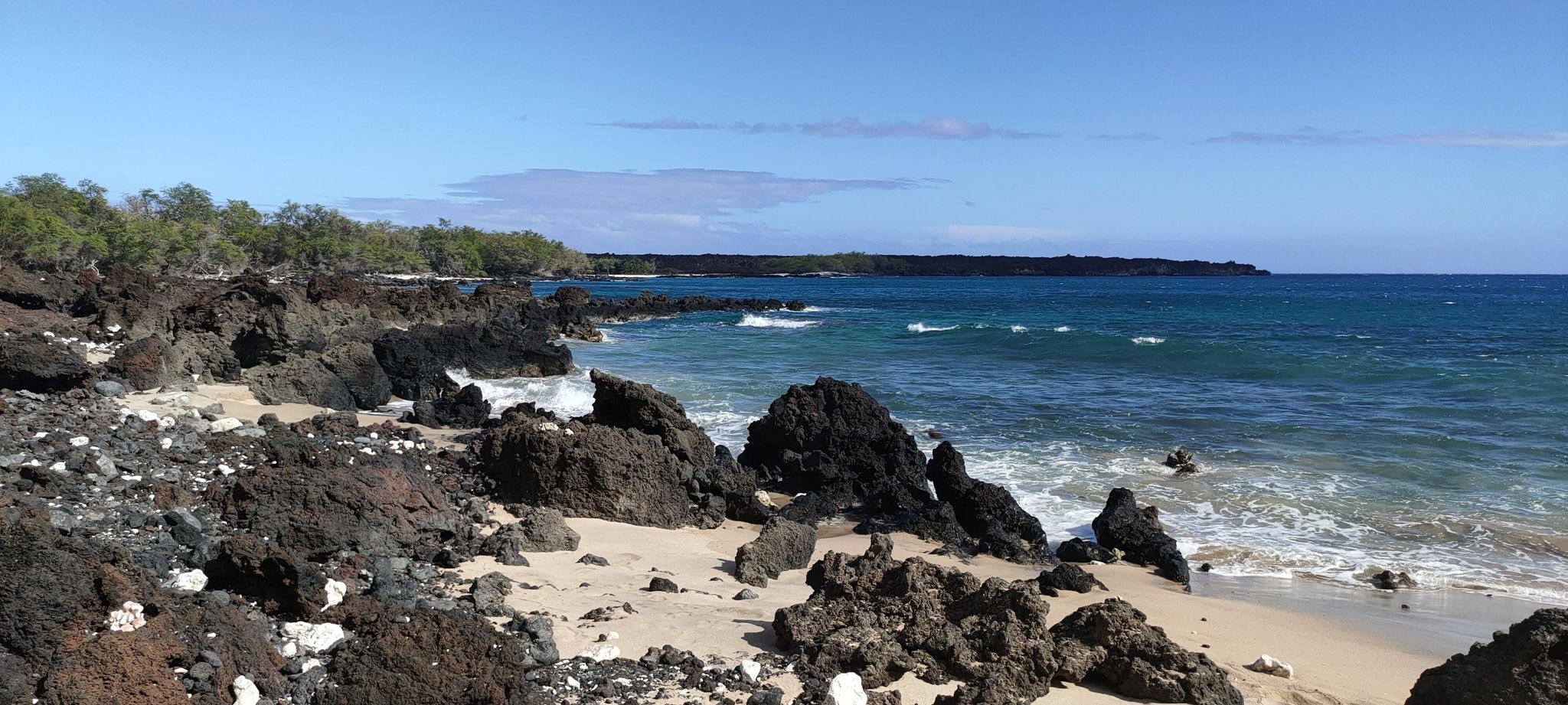 Sunny coastal landscape with dark lava rocks, sandy beach, and blue ocean. - Hoapili Trail to Hanomanioa Light