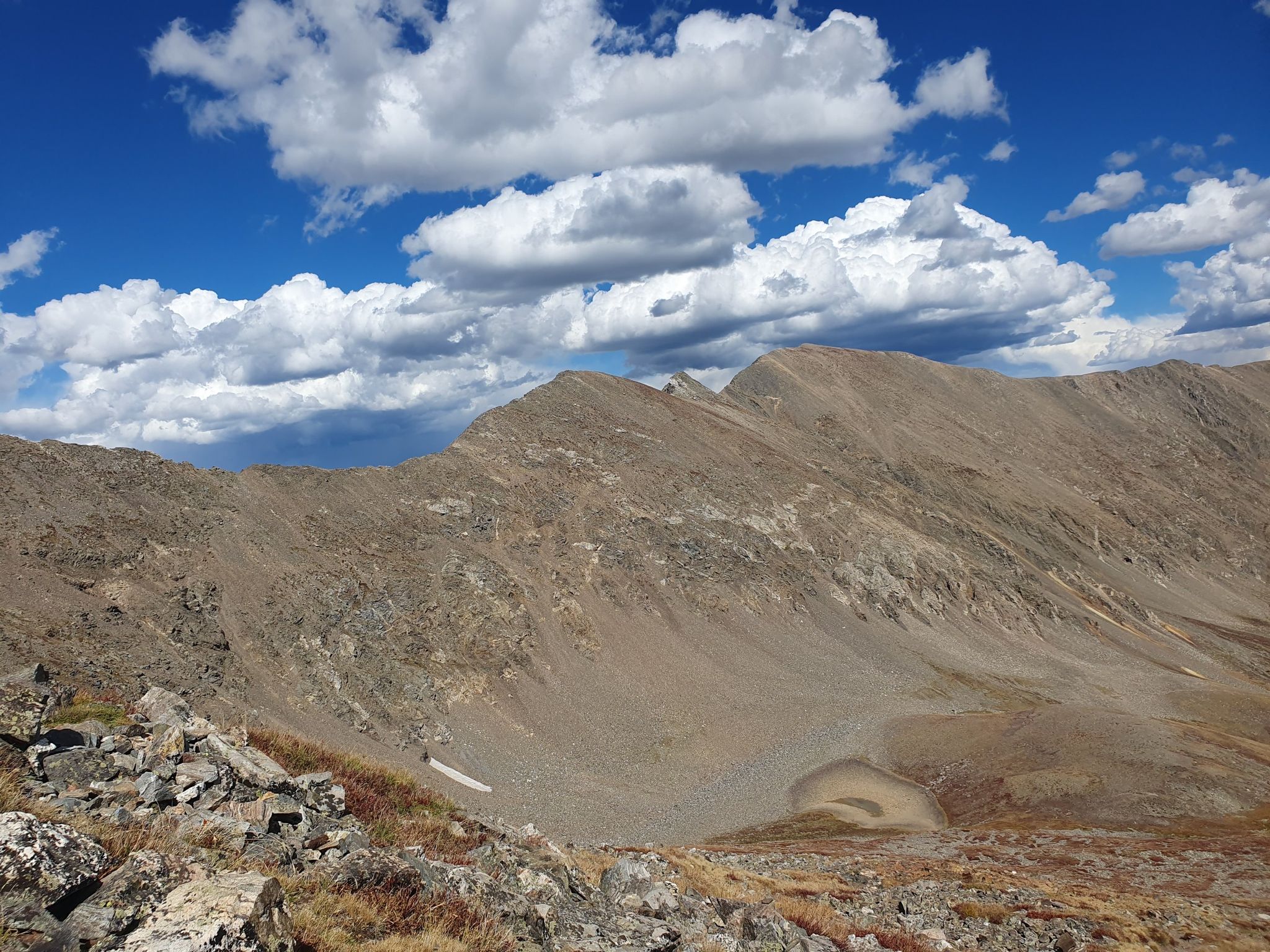 Rocky mountain range under a partly cloudy sky, with a small basin lake. - Grays Peak & Torreys Peak from Argentine Pass Trailhead