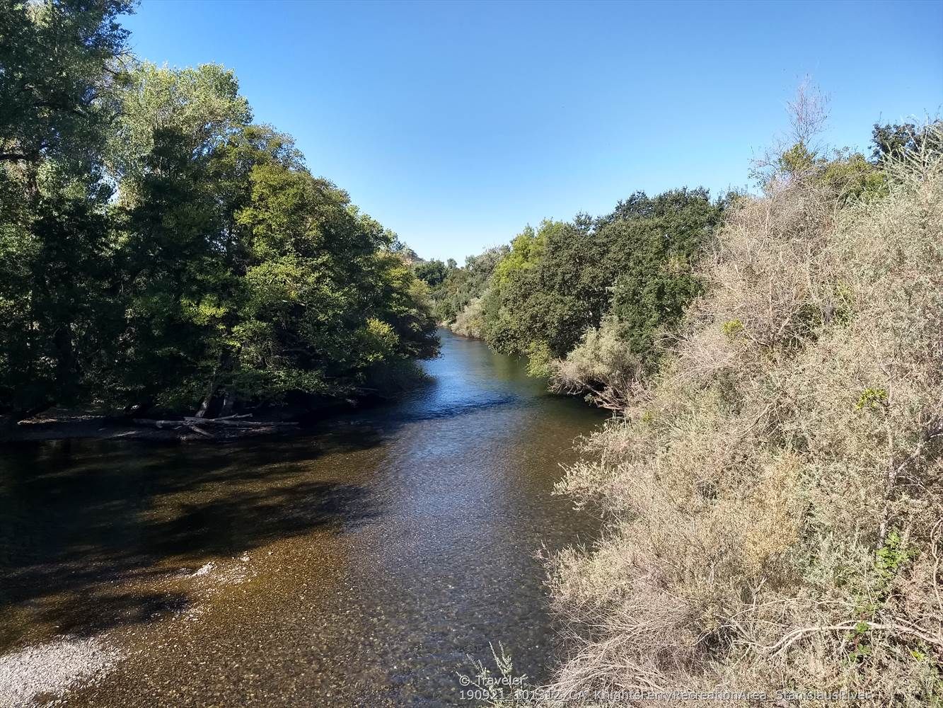 Clear river flowing between dense green and dry brush under a bright sky. - Russian Rapid Trailhead 🌊 – Stanislaus River Bridge loop from Roberts Ferry Union Elementary School