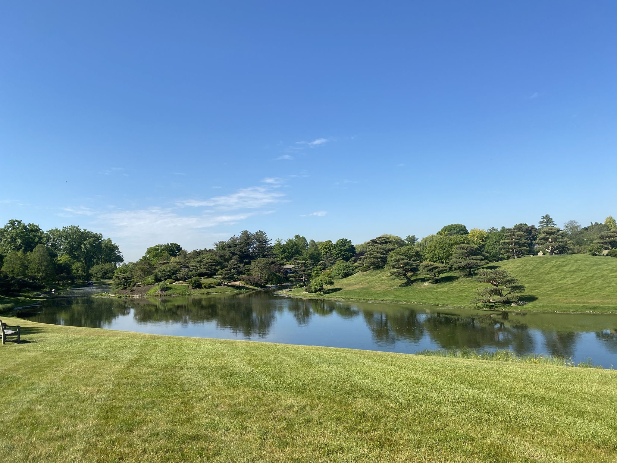 A serene lake with green hills and trees under a clear blue sky. - Skokie Lagoons – North Branch Trail loop from Fort Sheridan