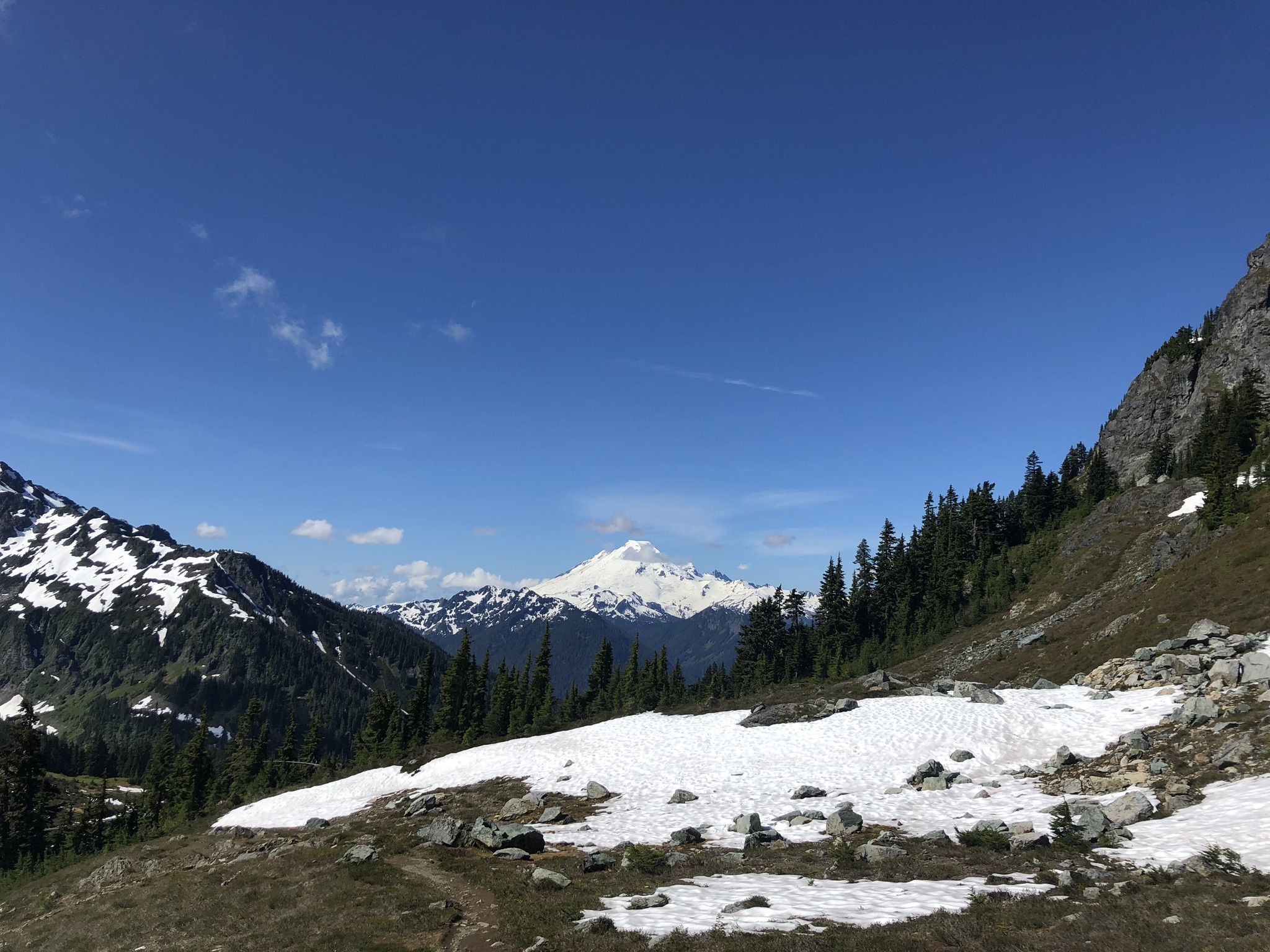 Distant snow-capped mountain under a clear blue sky, with foreground snow patches. - Winchester Mountain Trail