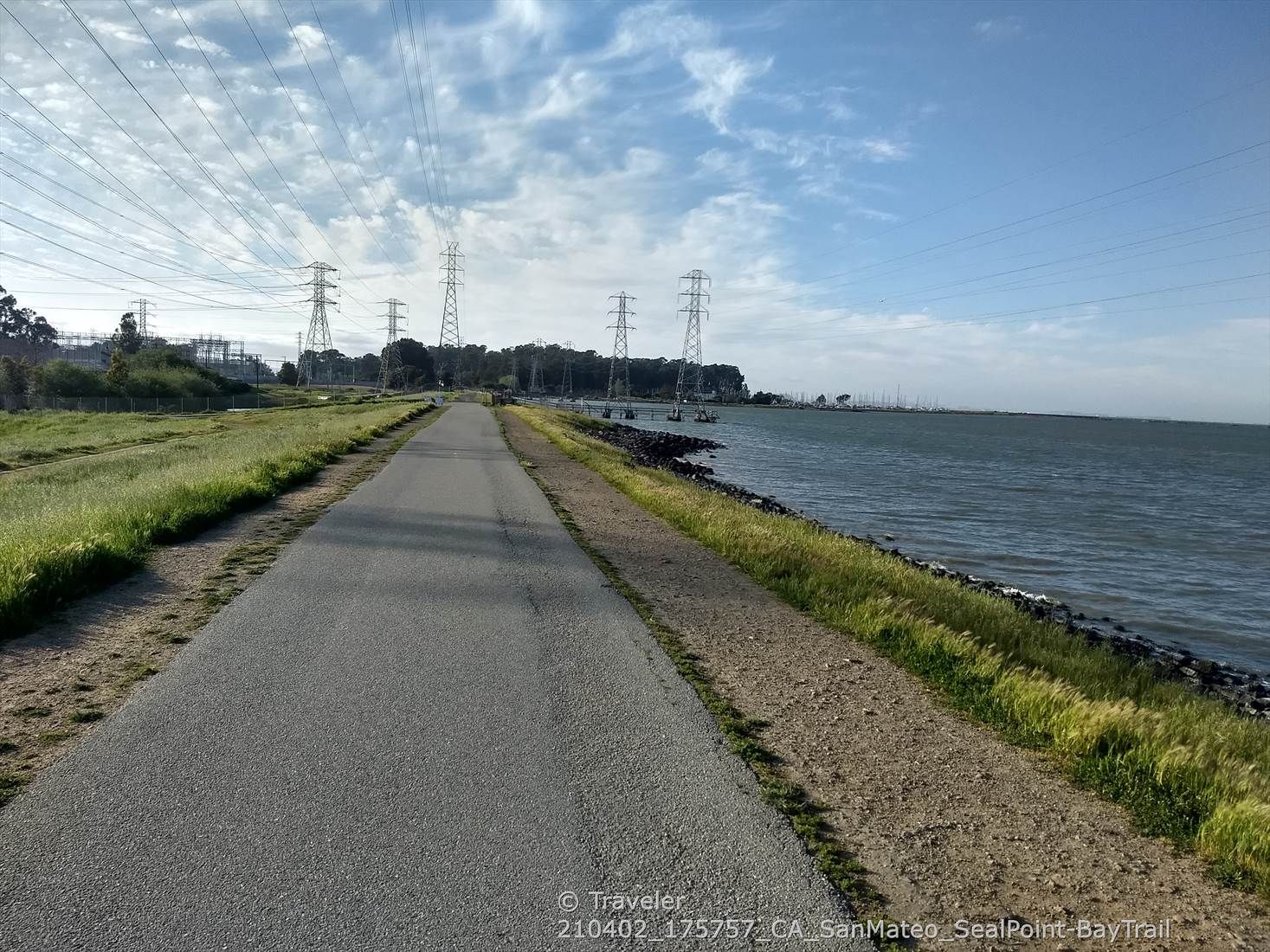 Paved path along the water, with power lines overhead and green grass. - Seal Point Park – Gerry Mon Memorial Path loop from Hayward Park