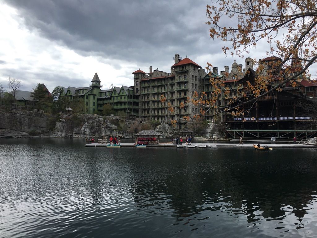 Large building overlooking a lake with a dock and people on a cloudy day. - Mohonk Preserve loop from New Paltz via Humpty Dumpty Road