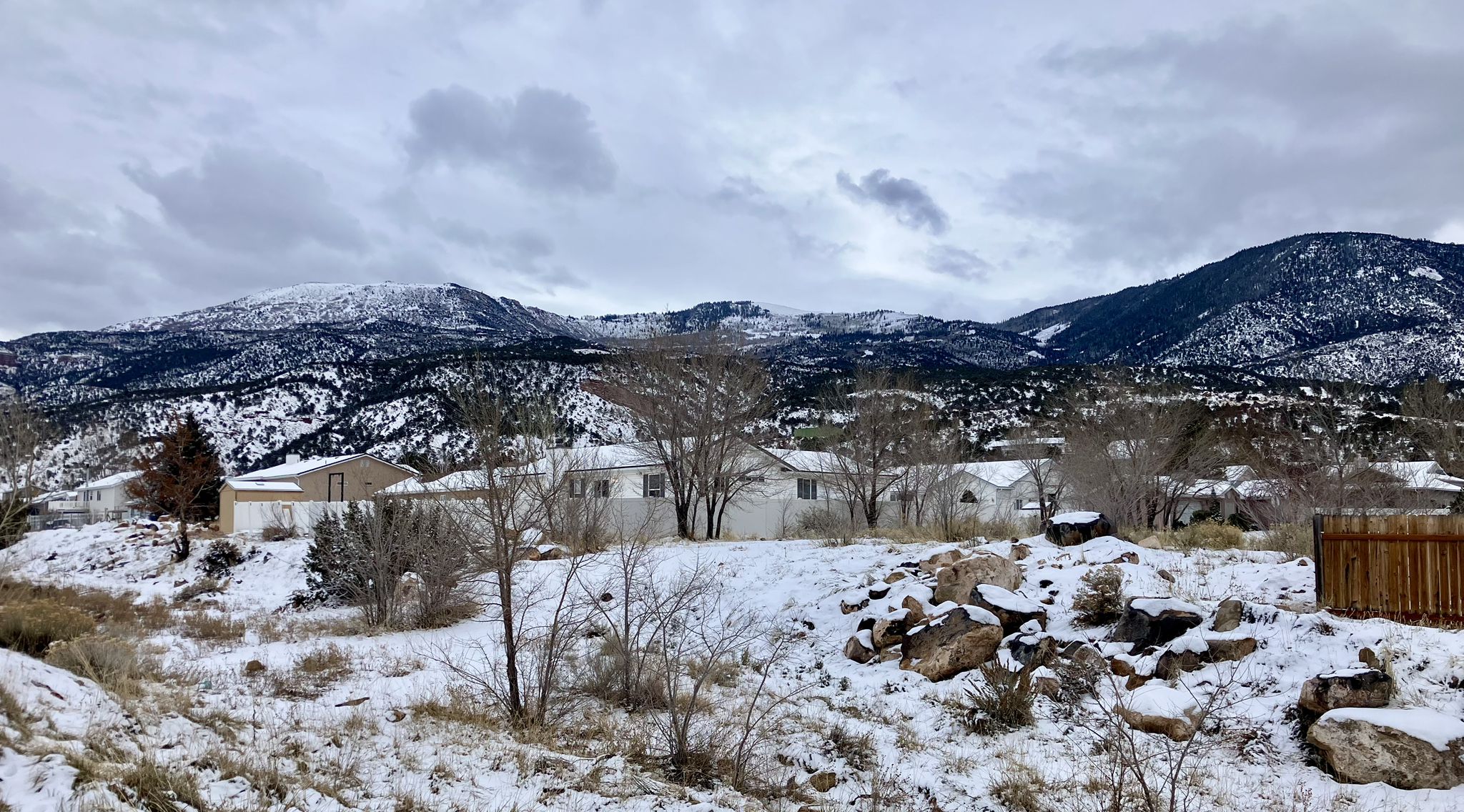 Snow-covered houses nestled among bare trees with distant snowy mountains. - Cedar Highlands loop