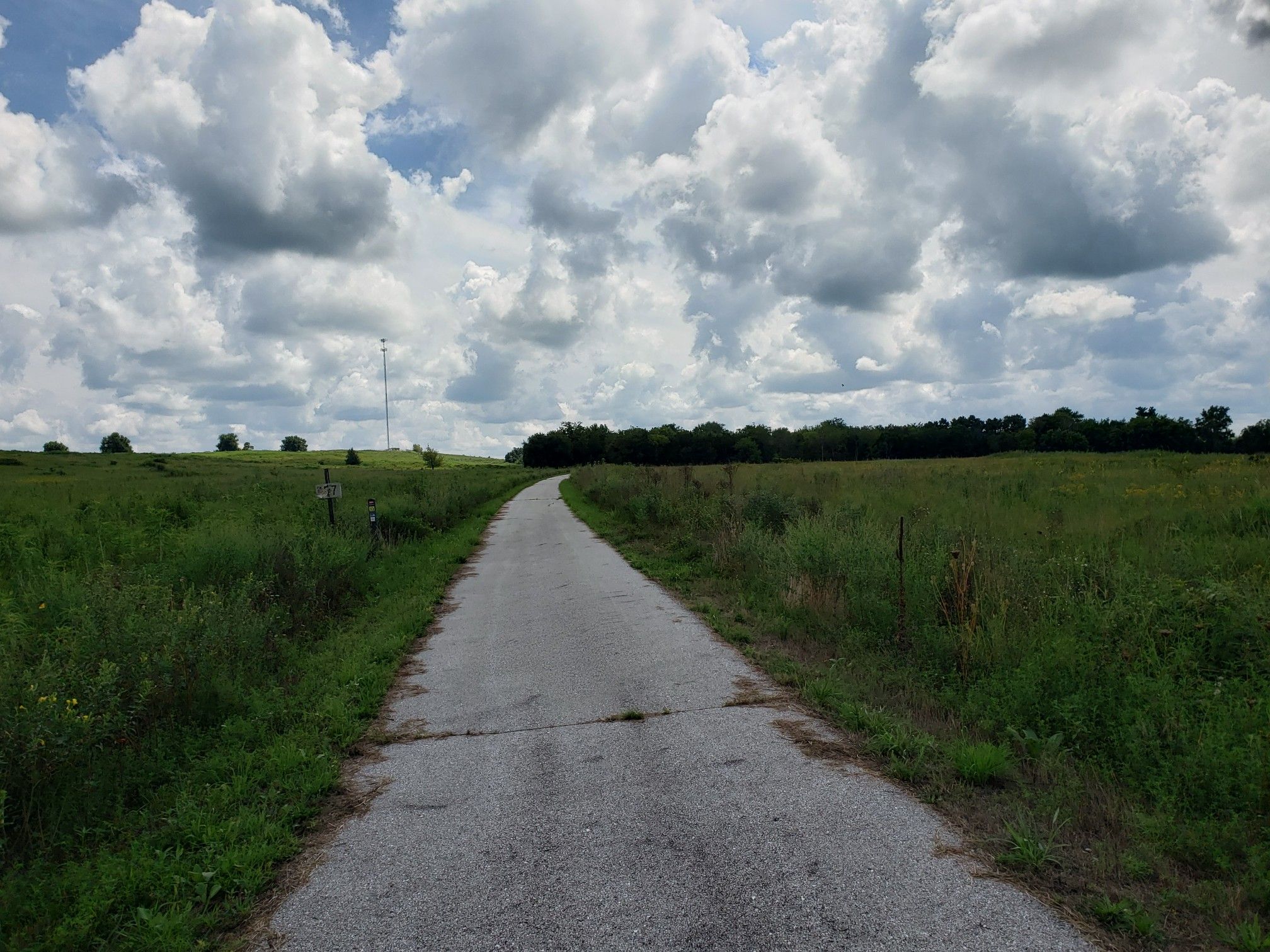 Paved path through green fields under a cloudy sky. - Frisco Highline Trail