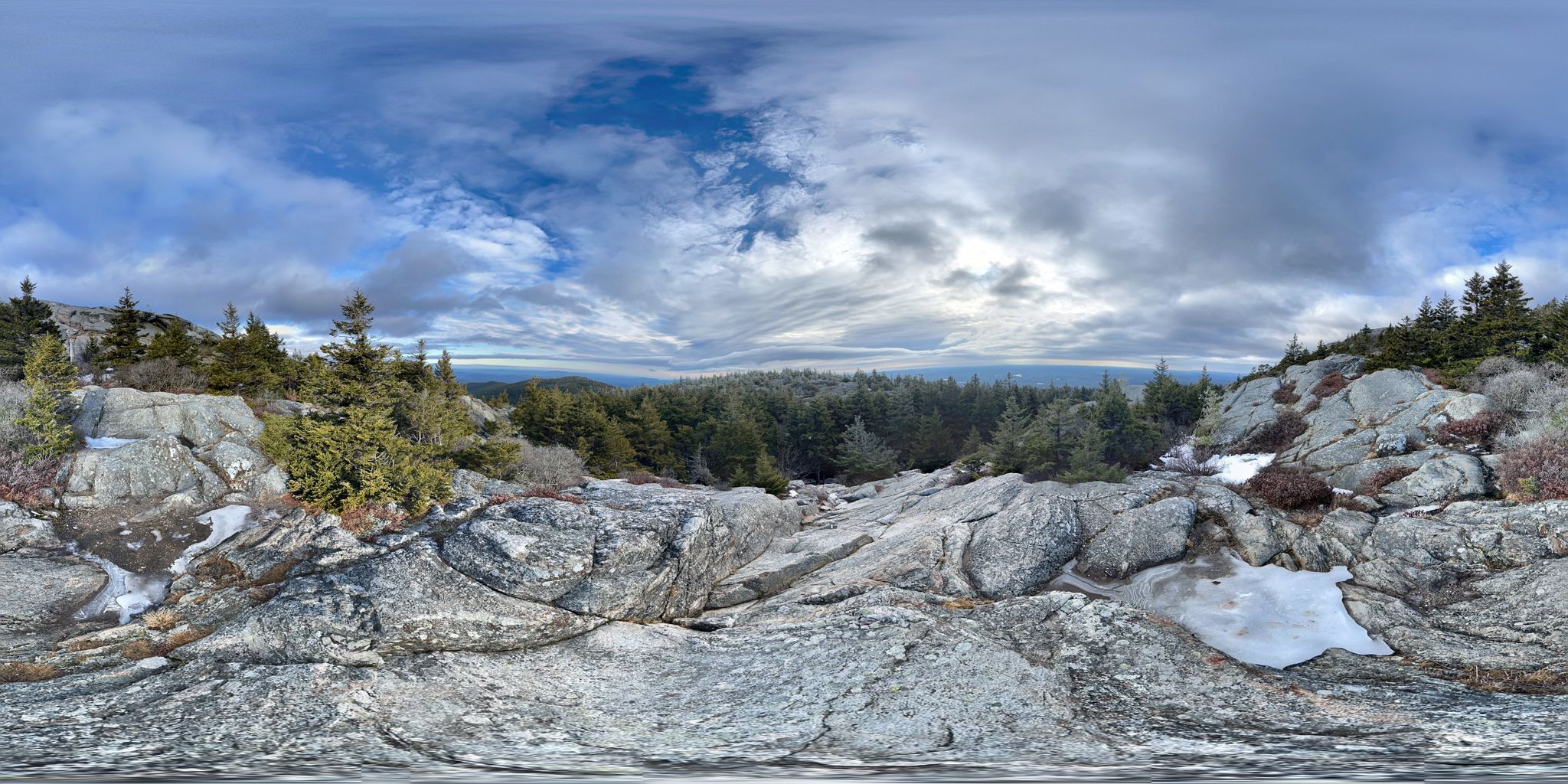 Panoramic view of a rocky, snowy mountain landscape with evergreen trees. - Pumpelly Trail