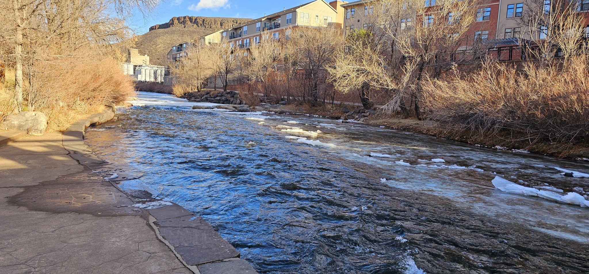 River flowing past bare trees and buildings under a bright sky. - Clear Creek Trail – Fairmont Canal Trail loop from Arvada West Dog Park