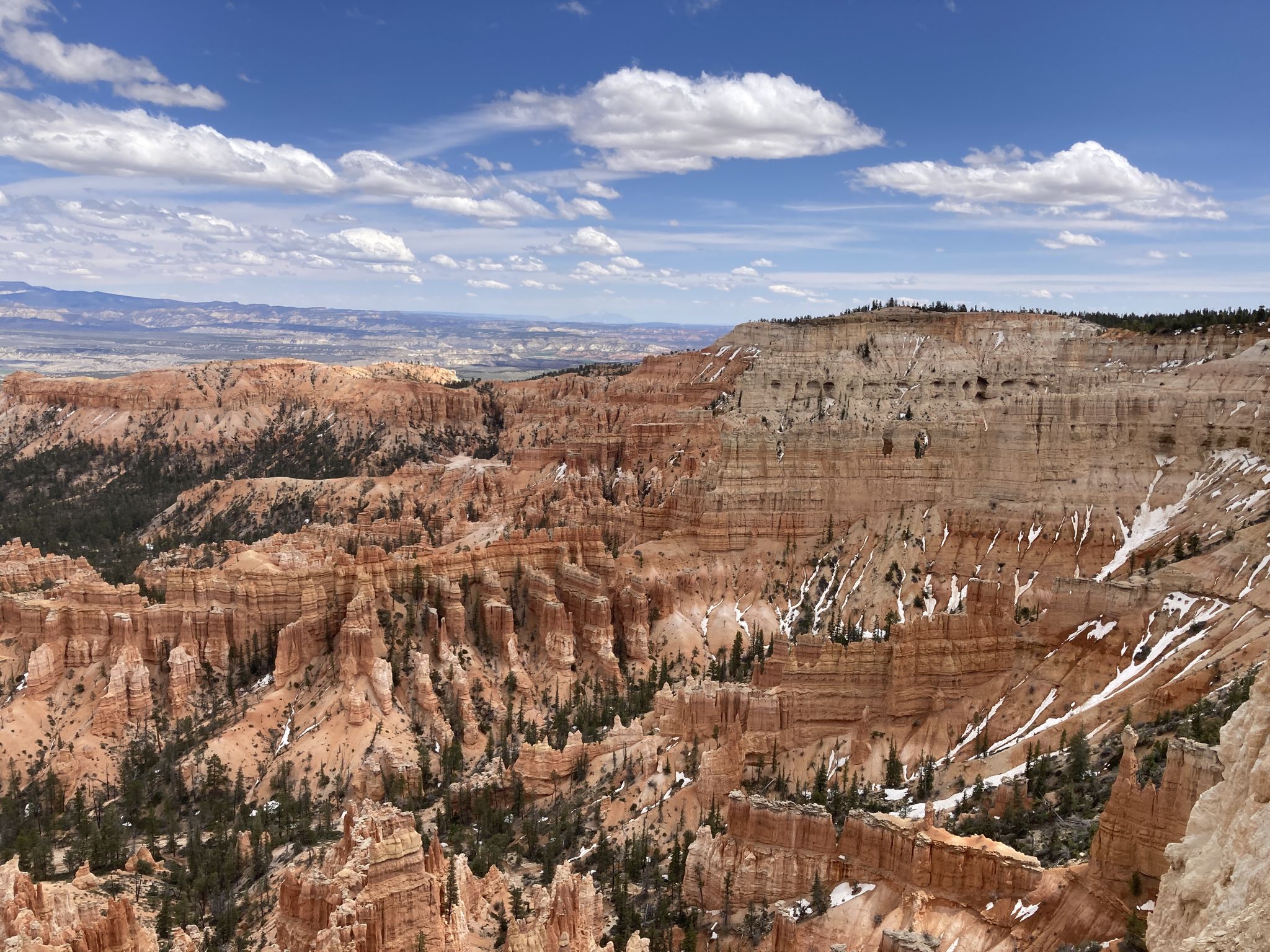Vast canyon with orange and white rock formations under a blue sky. - Lower, Mid, and Upper Inspiration Points