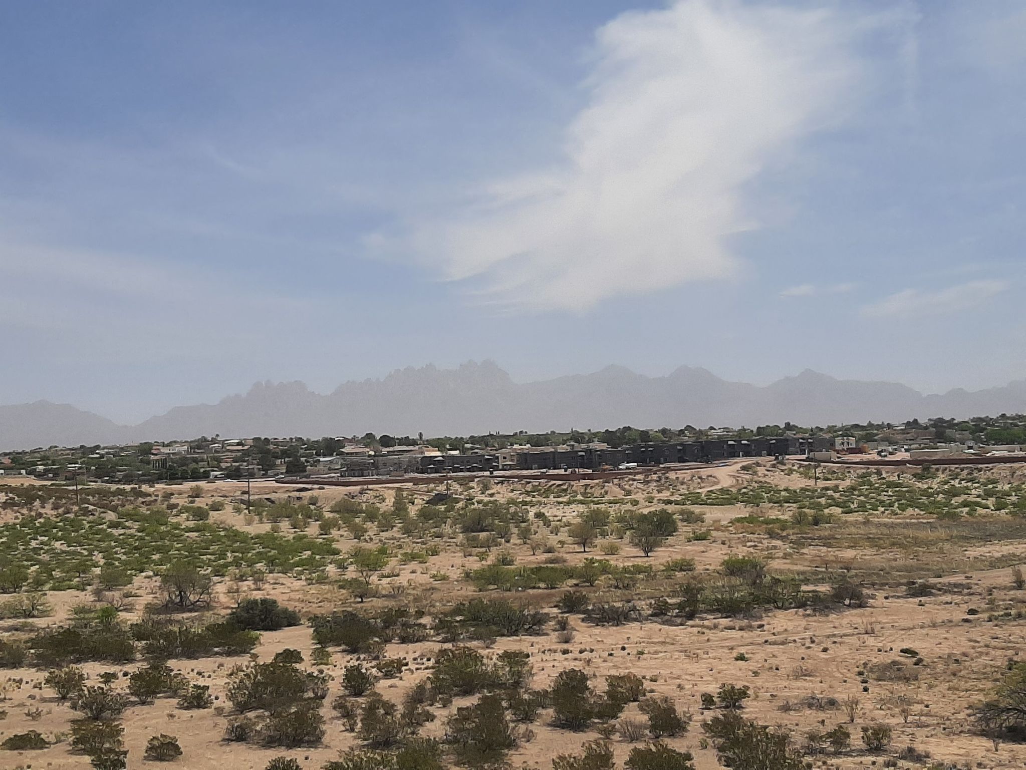 Vast desert landscape with sparse vegetation, distant mountains, and buildings. - Las Cruces Dam – Dam Trail loop from Shell