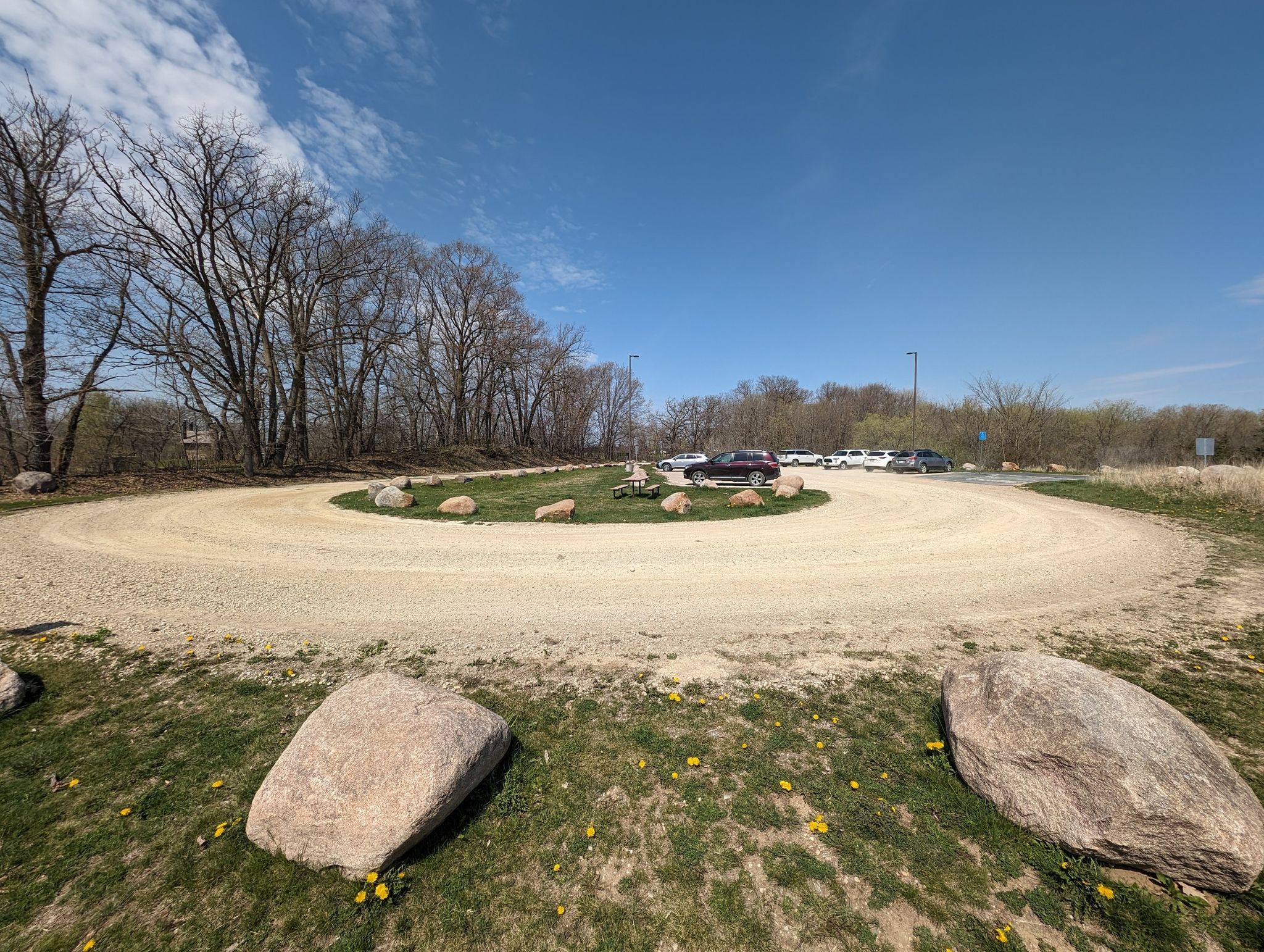 Circular gravel parking area with cars, large rocks, and bare trees. - Spring Lake Regional Trail