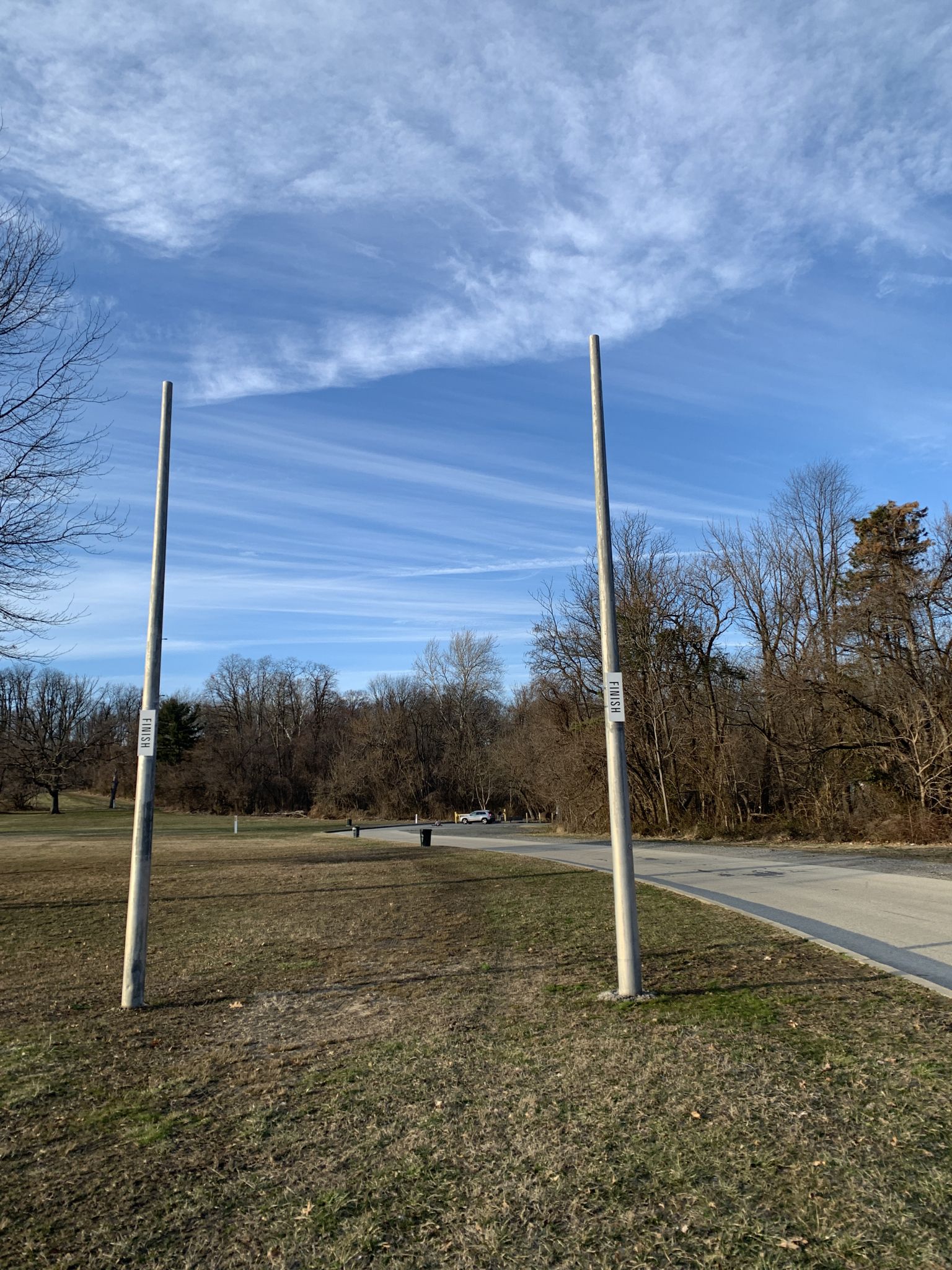 Two tall posts stand in a grassy field under a bright blue sky. - Trolley Trail Loop