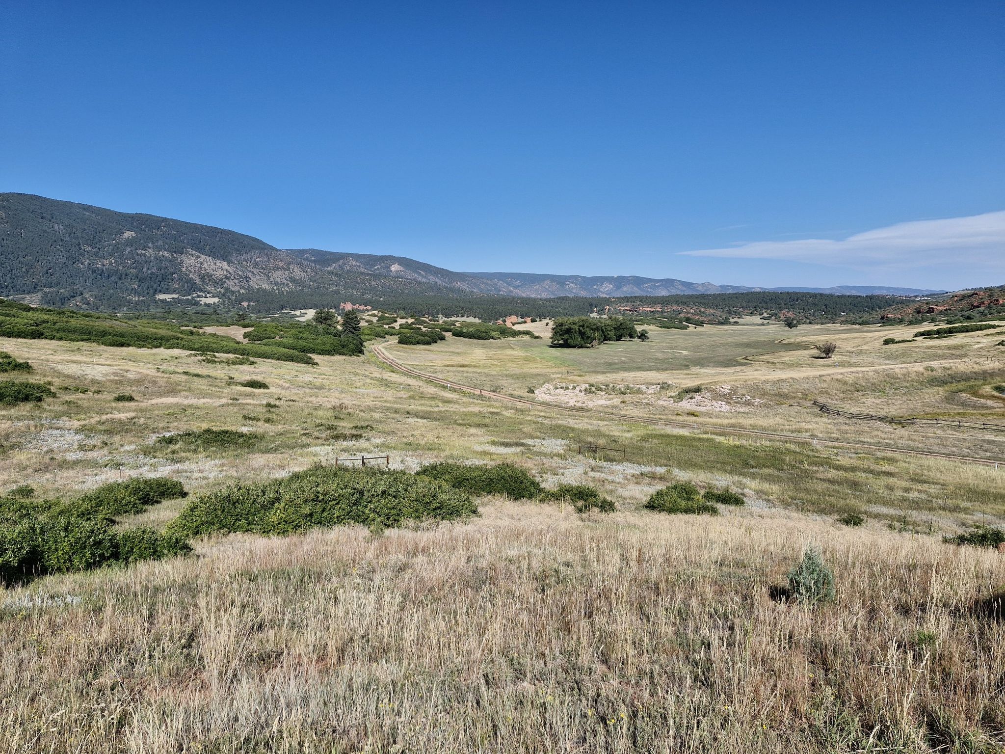 Sunny wide shot of a vast grassy valley with distant mountains. - Sandstone Meadow Trail Loop