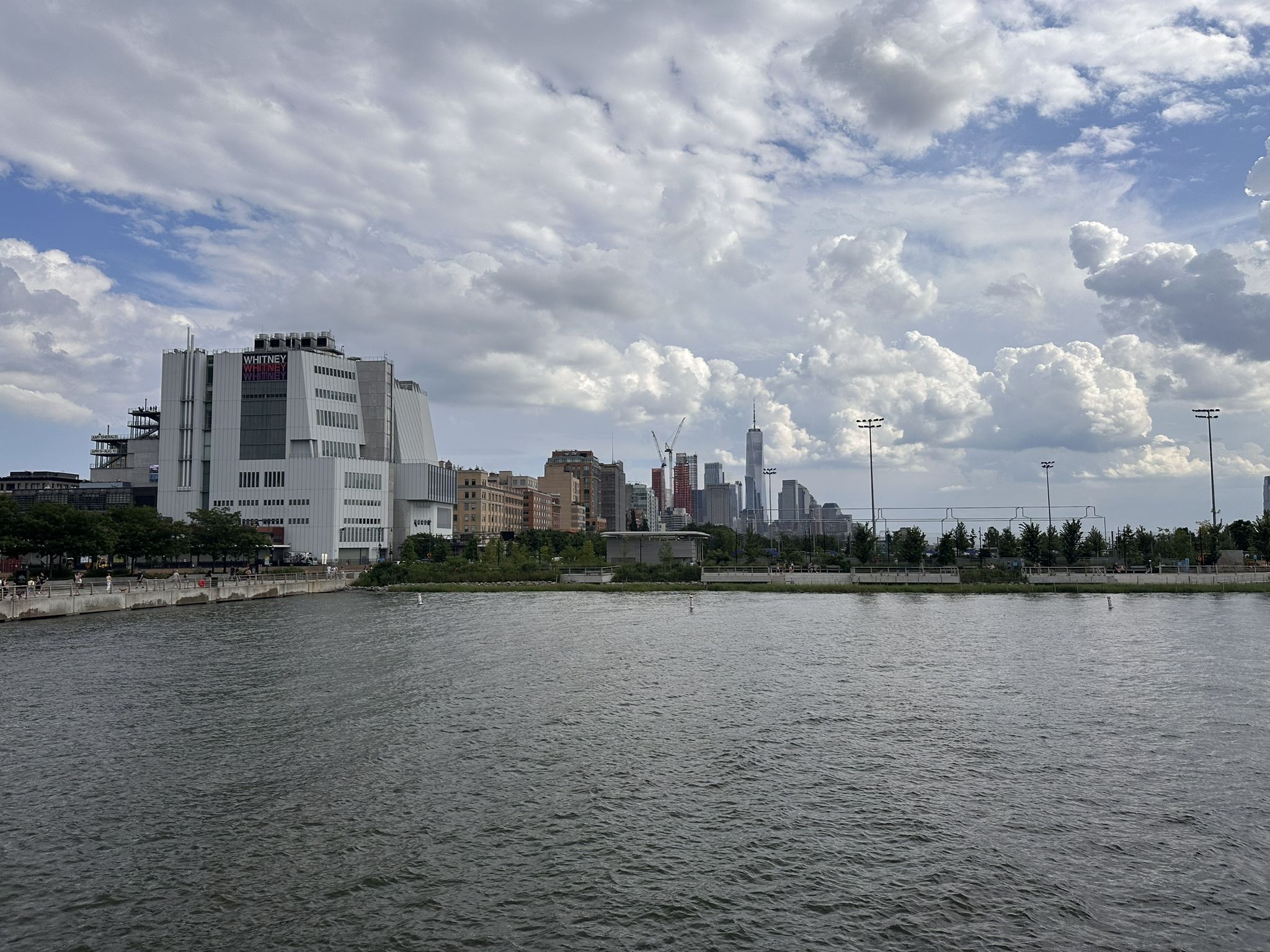 A large white building by the water, with a distant city skyline under clouds. - Little Island at Pier 55 – The Vessel, Hudson Yards loop from Manhattan