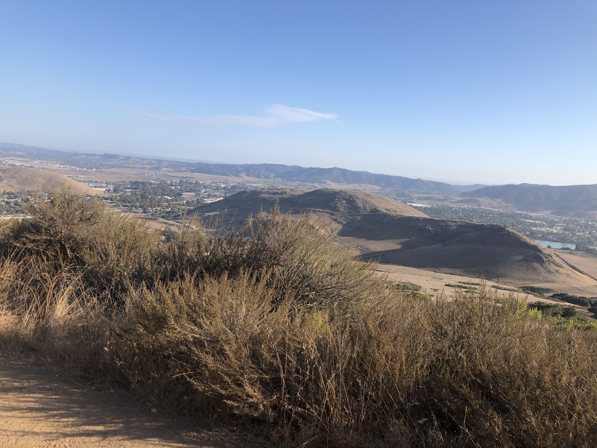 Expansive view of dry hills overlooking a distant town under clear sky. - Cerro San Luis Loop
