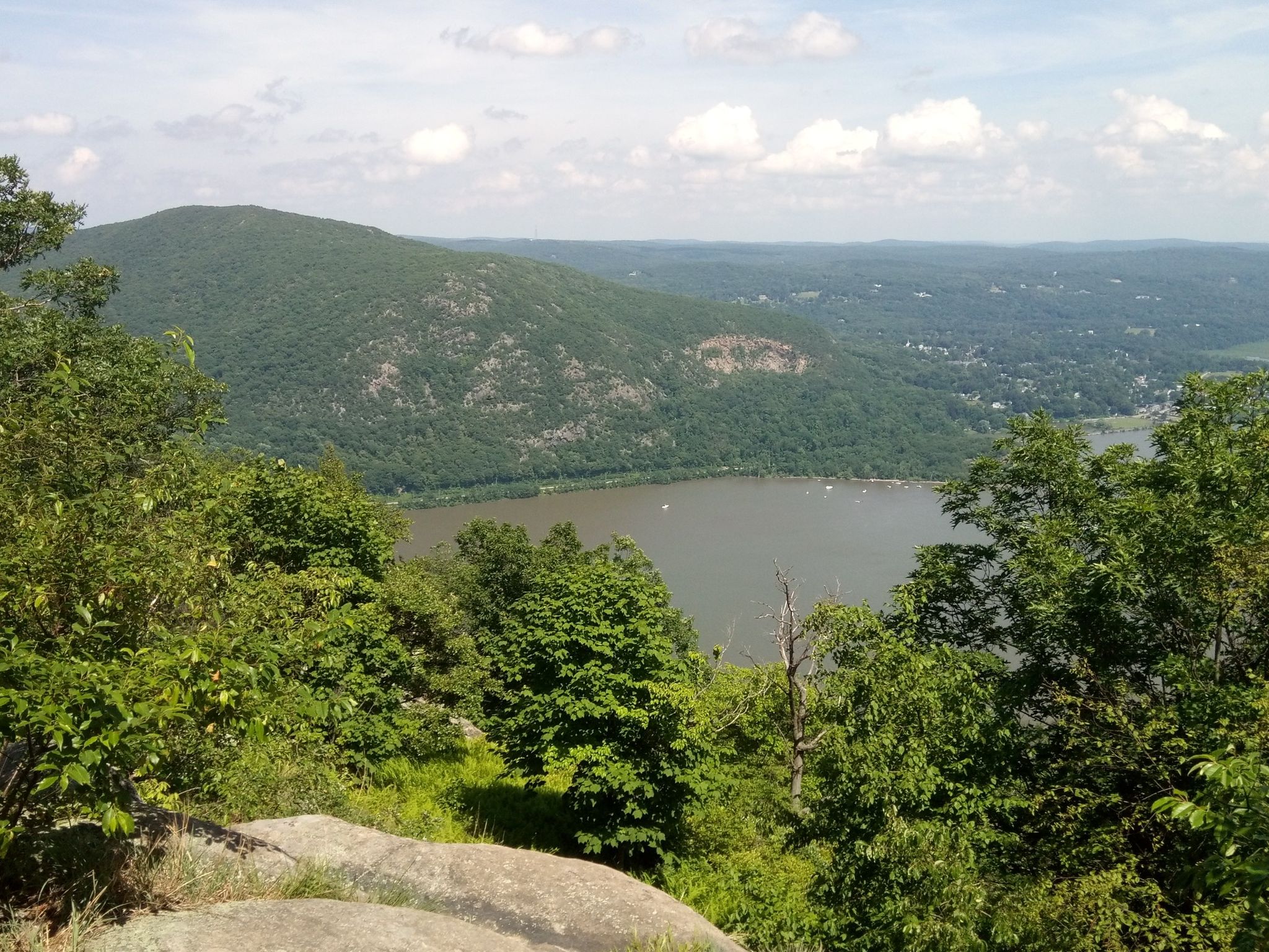 Wide river flows between lush green mountains under a cloudy sky. - Bypass Trail