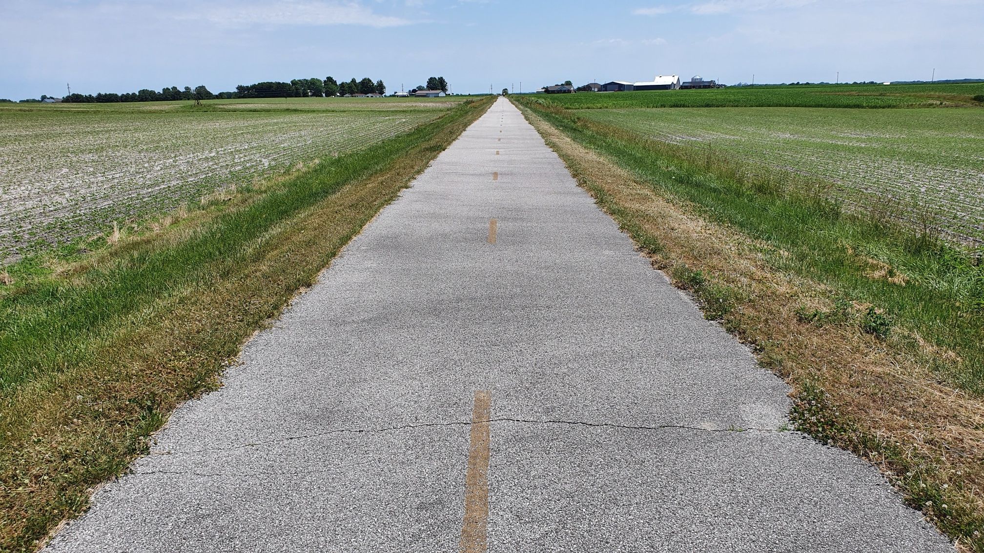 A long, straight paved path extends through flat green fields under a cloudy sky. - MCT Heritage Trail – Marine Heritage Park loop from Southern Illinois University Edwardsville